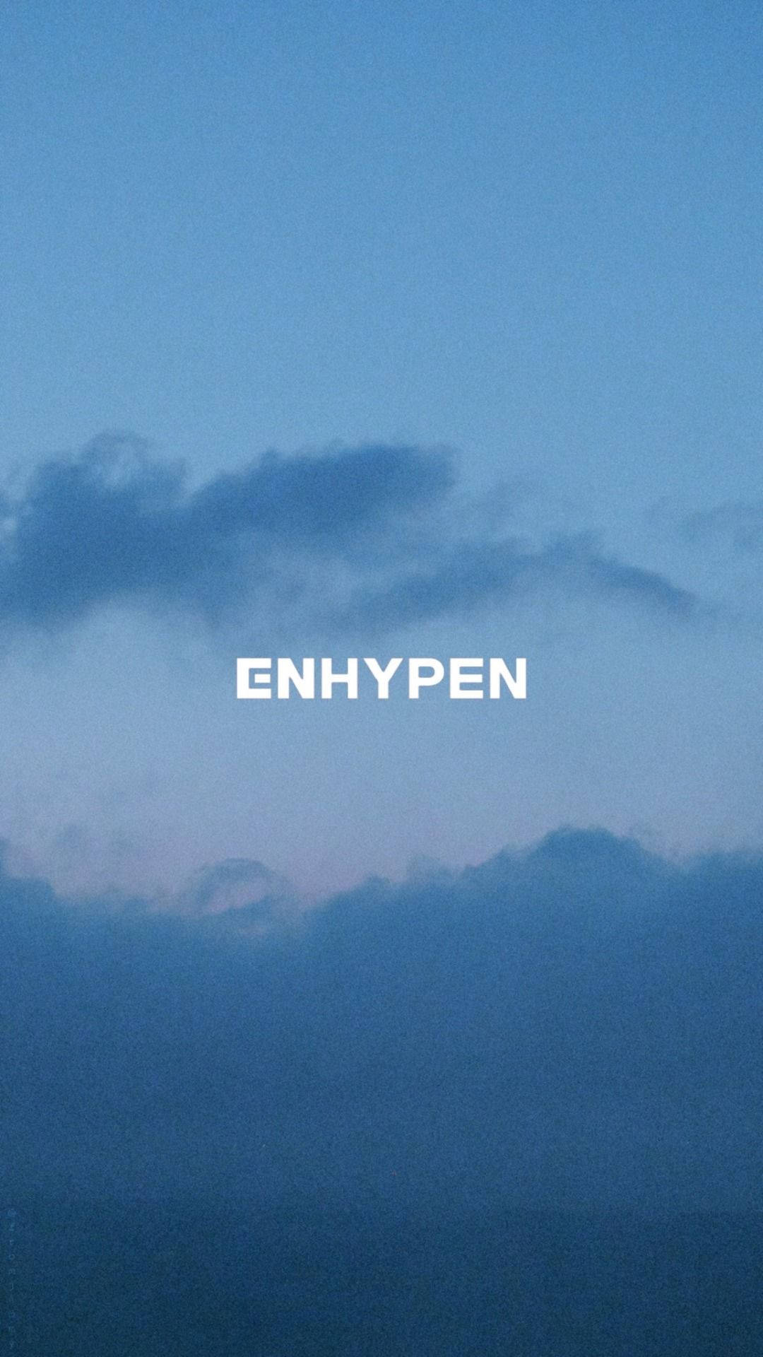 Enhypen Aesthetic 桌布 壁紙 — 寧靜的暮色天空，帶有柔和的藍色雲朵，以及文字ENHYPEN背後微妙的粉紅色光芒。