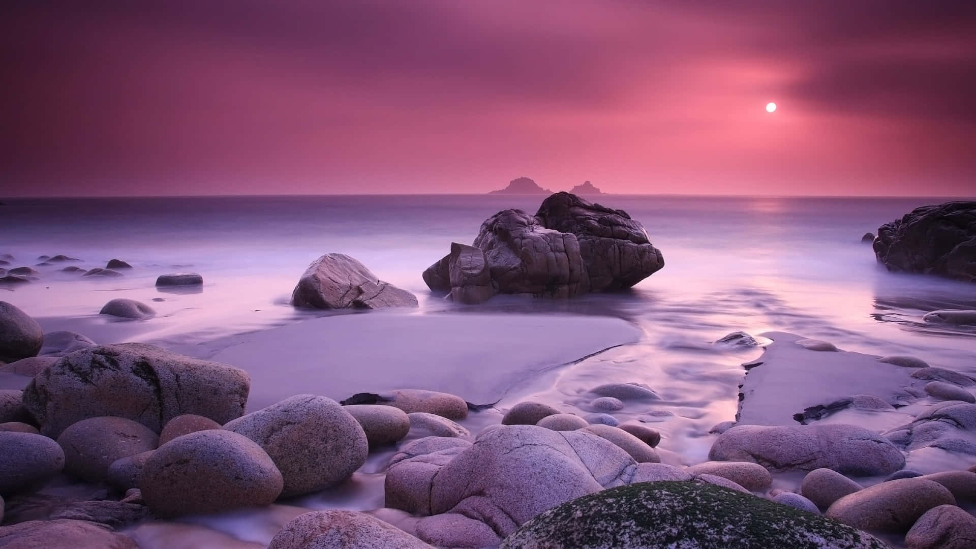 Relaxing Desktop 桌布 壁紙 — 寧靜的海岸日落景色，平滑的水流繞過大石，在充滿活力的粉紅色天空下。