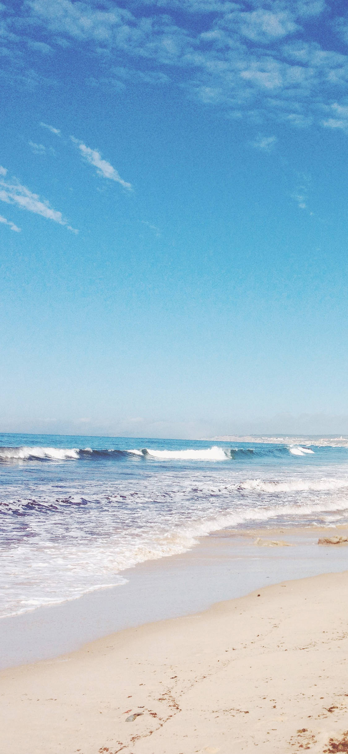 iPhone X Beach 桌布 壁紙 — 寧靜的海灘景色，在廣闊的藍天和薄雲下，碧綠的海浪拍打著金色的沙灘。