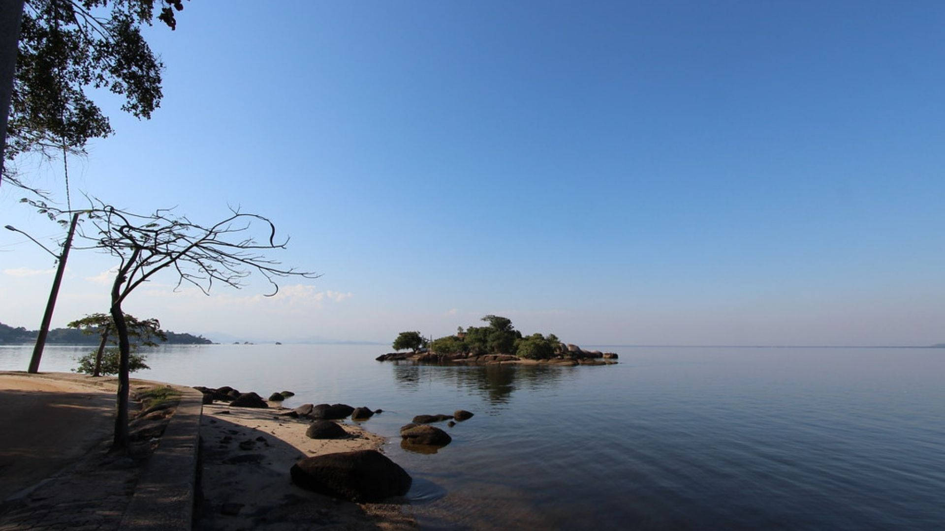 迦納 桌布 壁紙 — 寧靜的湖邊景色，藍天白雲下有一個小樹島。