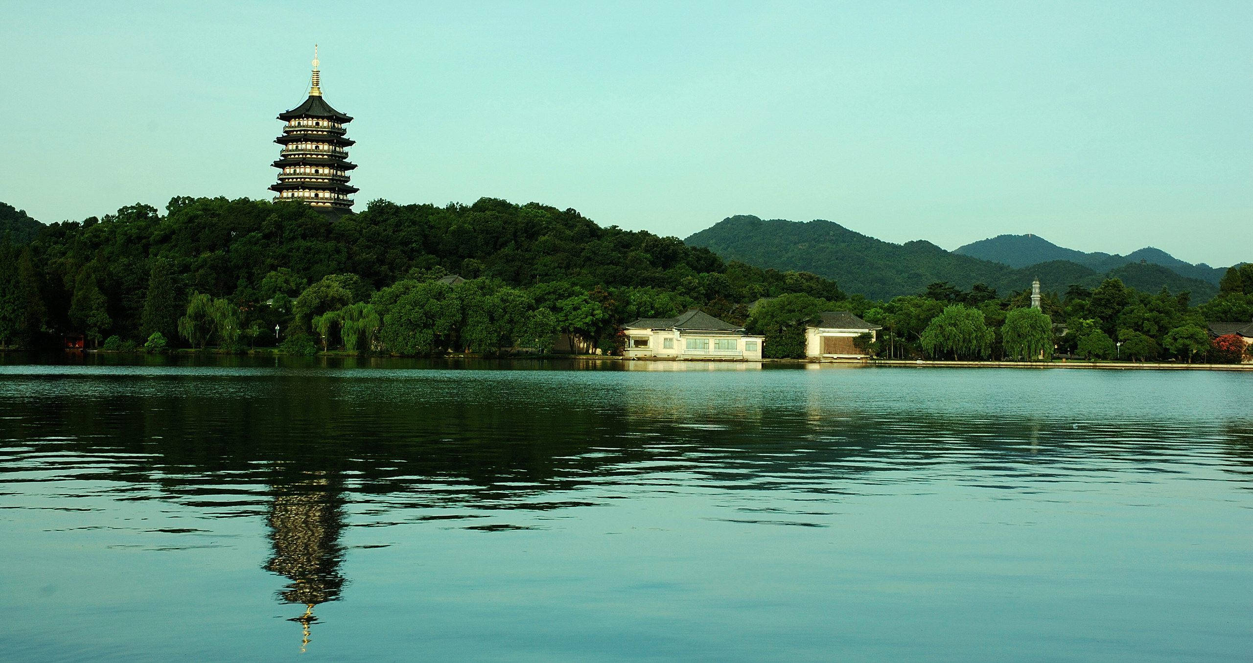 Hangzhou 桌布 壁紙 — 寧靜的湖面倒映著一座傳統寶塔，矗立於翠綠山丘之巔，天空清澈。