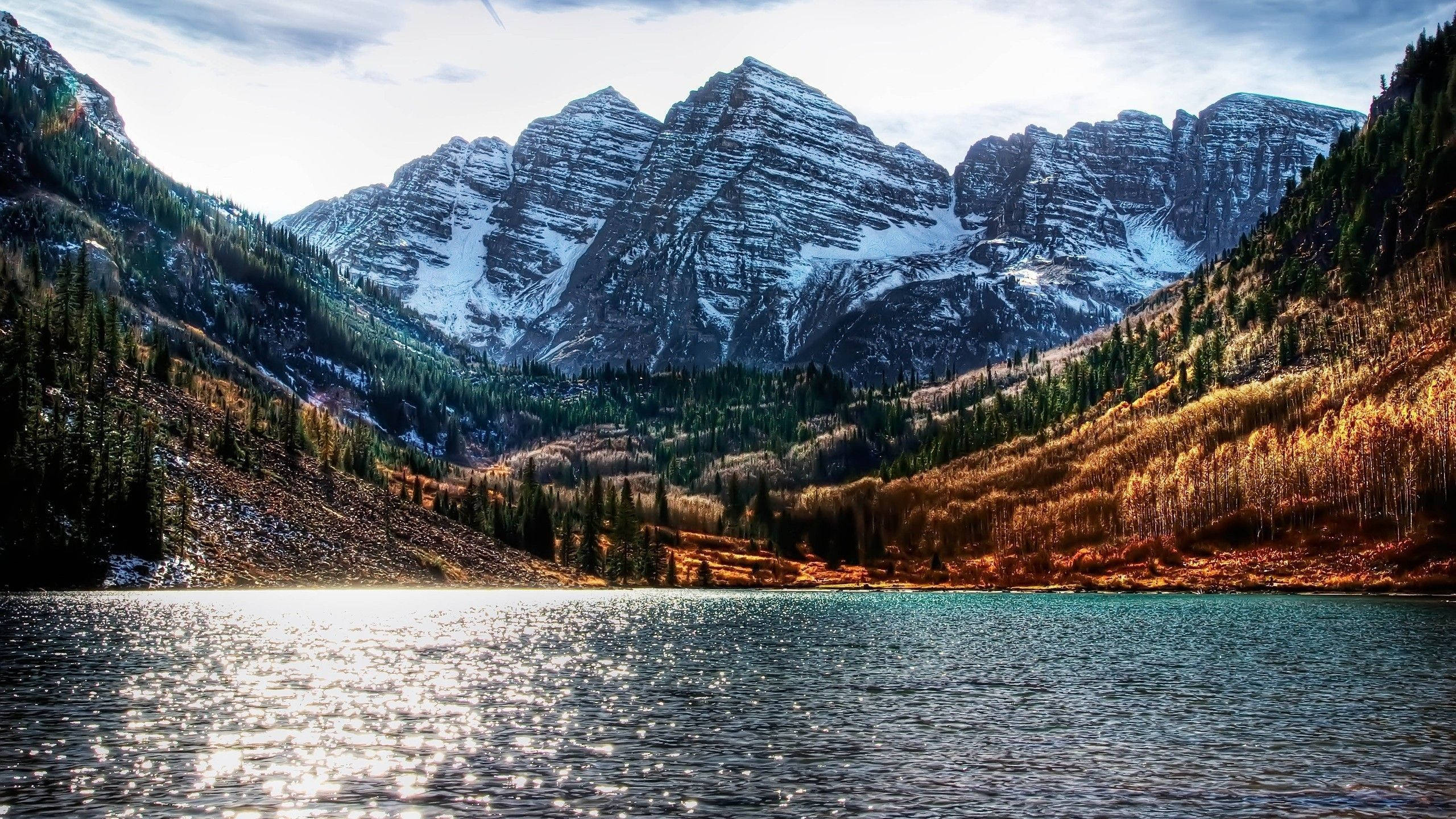 Colorado 桌布 壁紙 — 寧靜的湖面倒映著白雪覆蓋的山峰，天空明亮，金色的秋樹排列在湖岸邊。