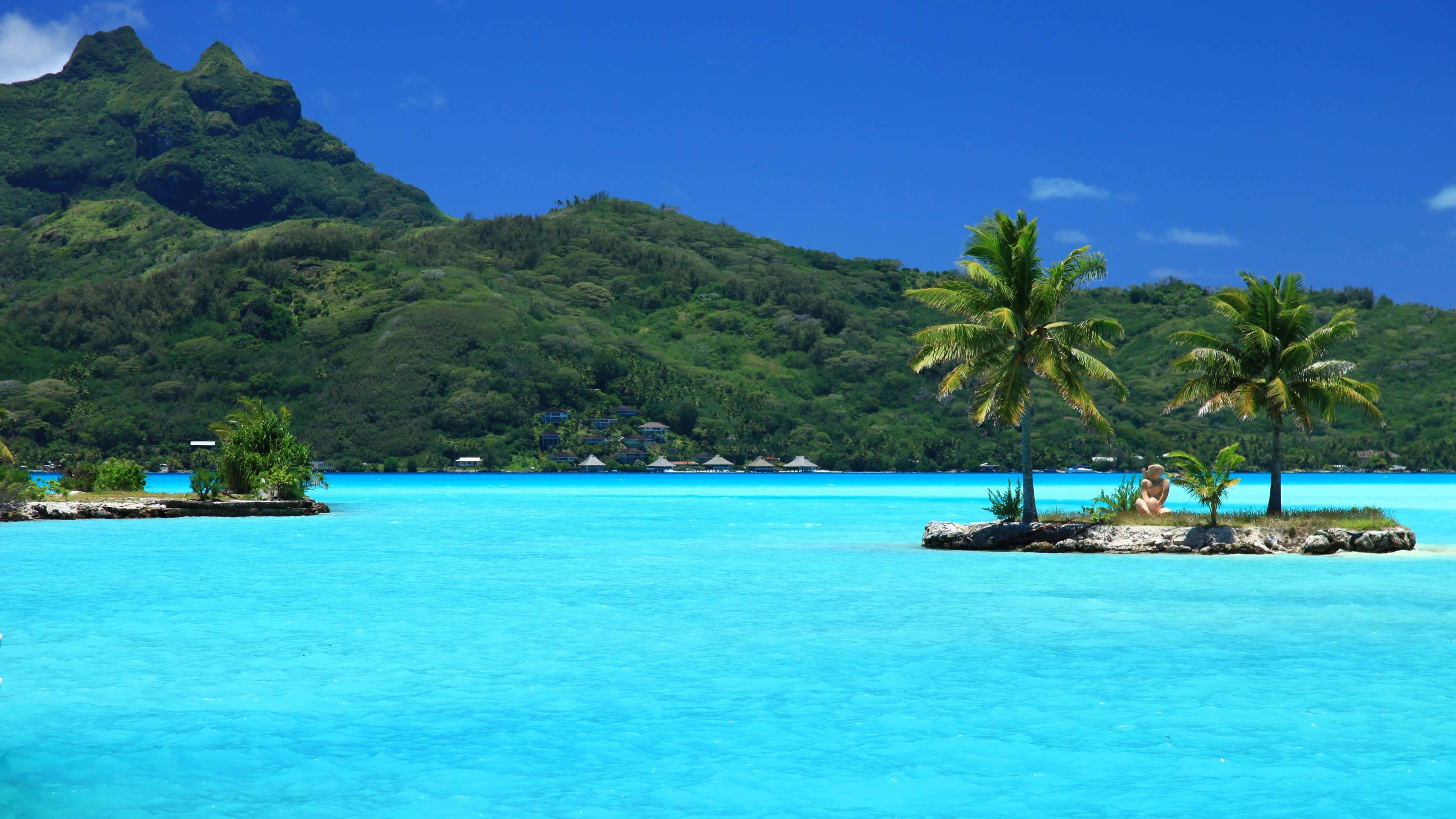 Bora Bora 桌布 壁紙 — 寧靜的熱帶天堂，擁有碧綠色的潟湖、棕櫚樹環繞的小島和晴朗藍天下鬱鬱蔥蔥的綠色山脈。