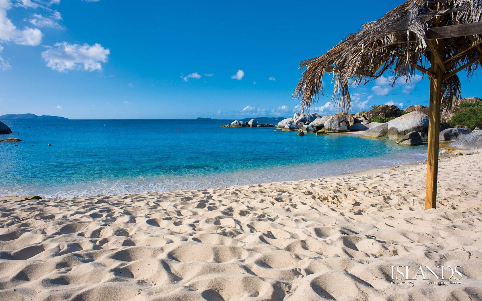 Turks And Caicos 桌布 壁紙 — 寧靜的熱帶海灘，碧綠的海水，溫柔的海浪，茅草遮陽傘在金色沙灘上投下陰影。