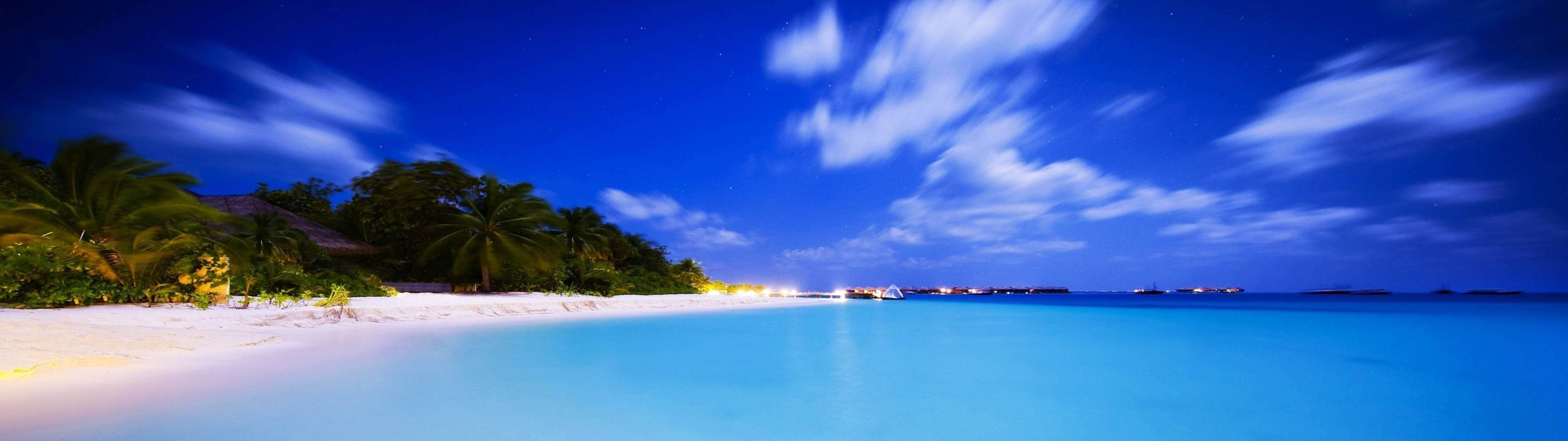 海灘 桌布 壁紙 — 寧靜的熱帶海灘夜晚，閃爍的碧綠海水、棕櫚樹和滿天星斗的天空，帶有條紋雲。