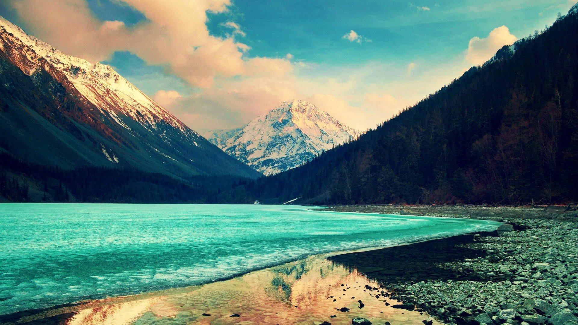 Lake 桌布 壁紙 — 寧靜的綠松石色湖泊倒映著白雪覆蓋的山峰，天空柔和湛藍，雲朵點綴其間。