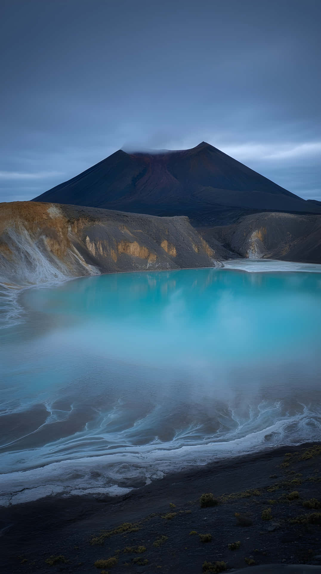 Surreal Volcanic Landscape with Turquoise Steaming Lake at Twilight 壁紙 — 寧靜的綠松色火山湖在陰鬱的暮色天空下映照著黑暗的山脈。