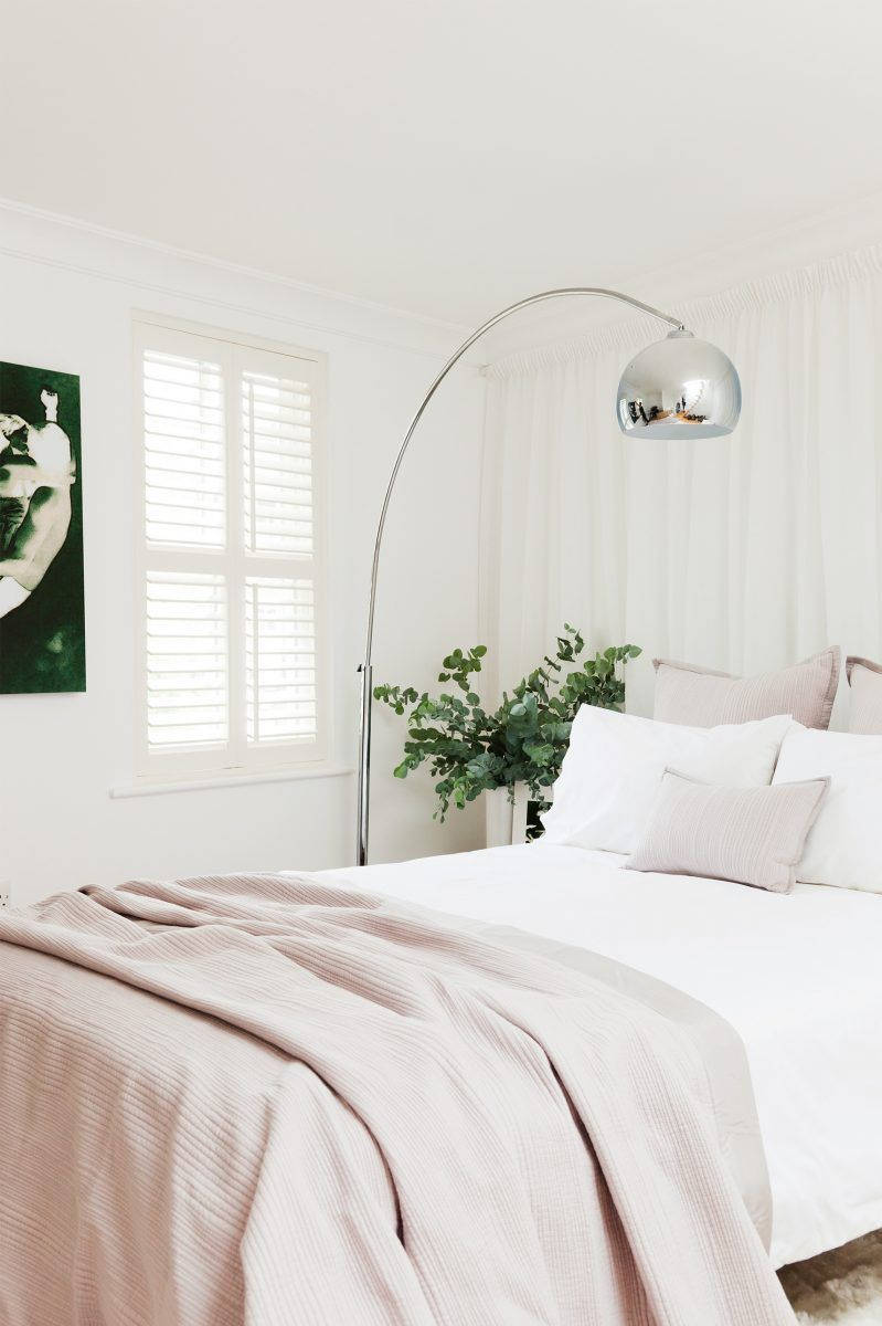 Aesthetic Bedroom 桌布 壁紙 — 寧靜的臥室，床上鋪著柔軟的粉紅色亞麻布，銀色弧形落地燈，白色百葉窗讓自然光線透入。