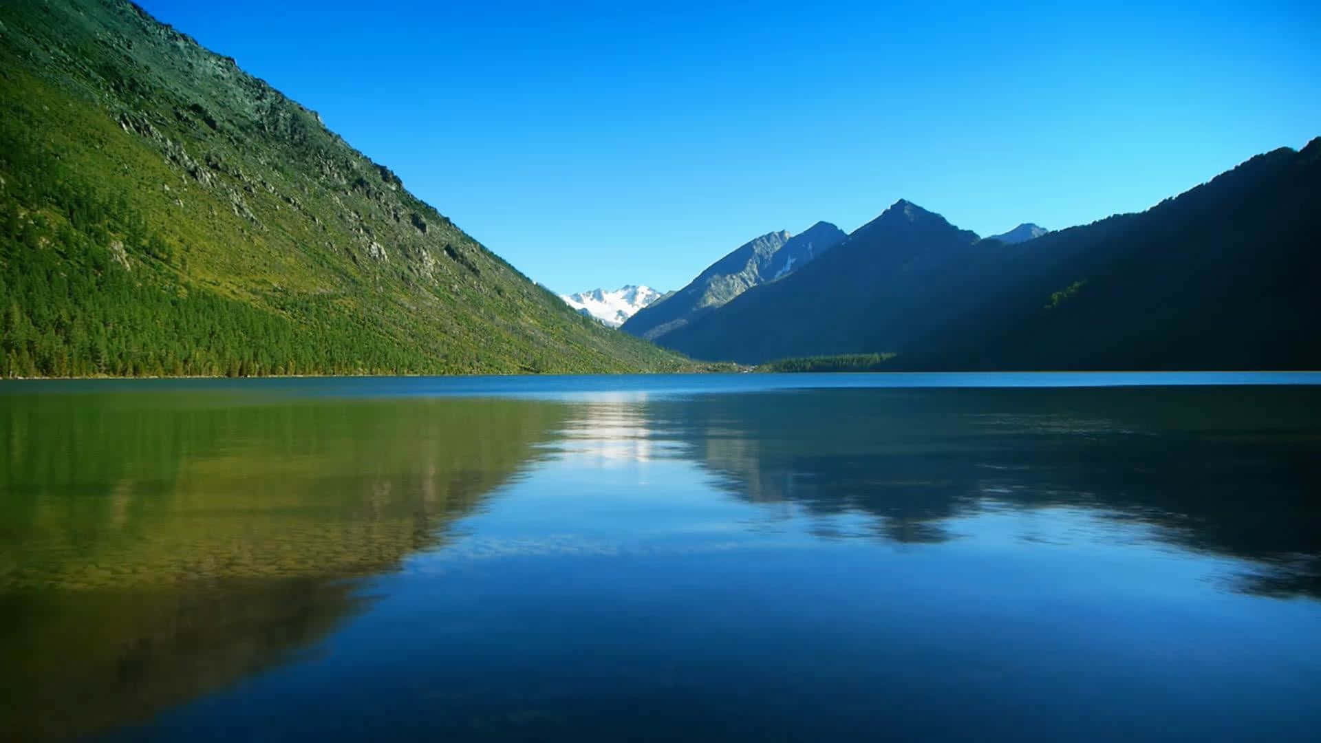 Calm 桌布 壁紙 — 寧靜的高山湖泊倒映著白雪覆蓋的山峰和翠綠的山坡，在清澈的藍天下。