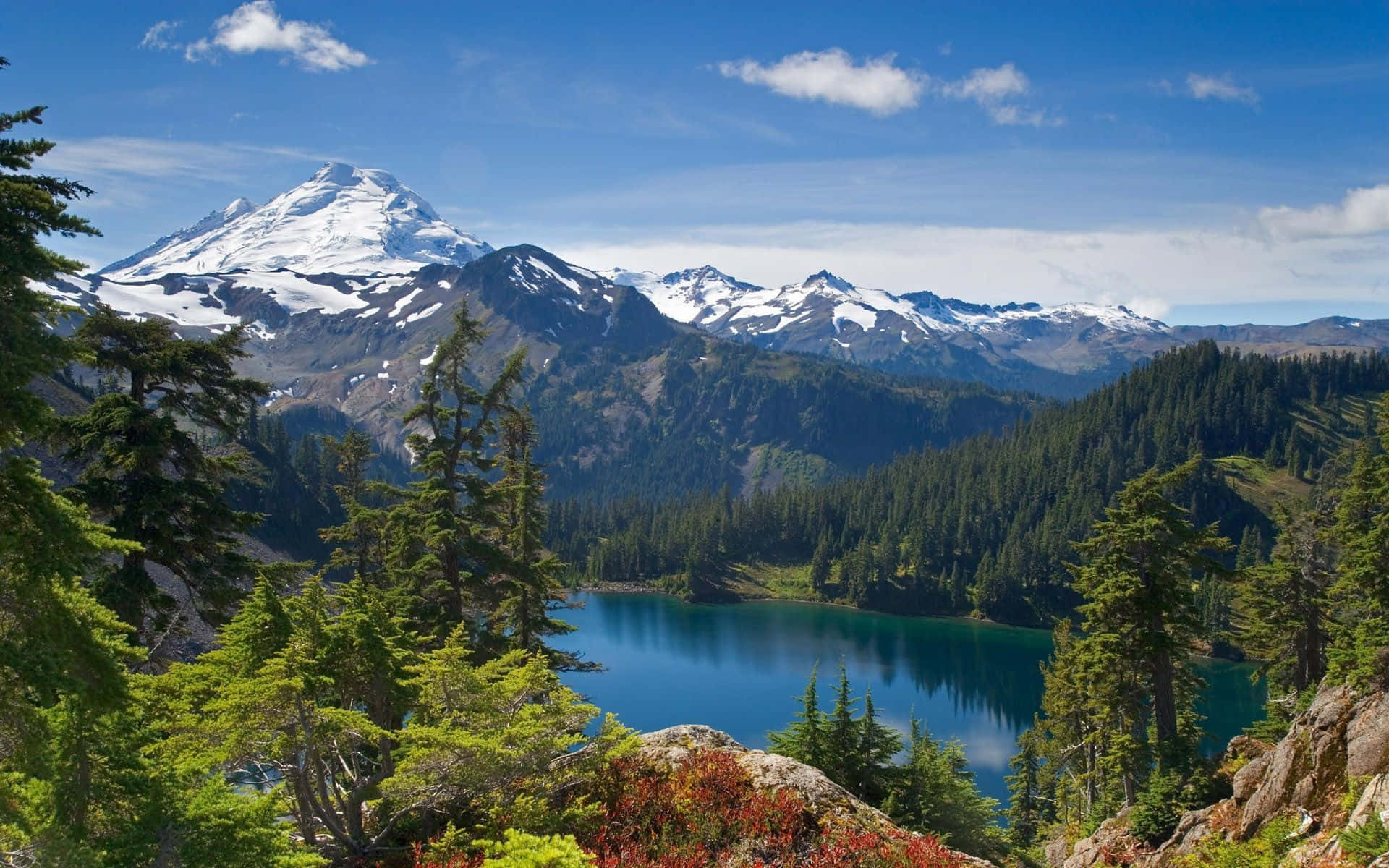 Forest Desktop 桌布 壁紙 — 寧靜的高山湖泊倒映著白雪覆蓋的山峰，天空湛藍，點綴著蓬鬆的白雲。