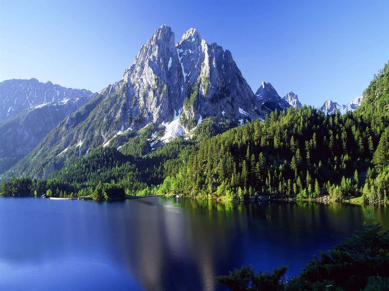 Montana 桌布 壁紙 — 寧靜的高山湖泊映照著白雪覆蓋的高聳山峰，天空清澈湛藍。