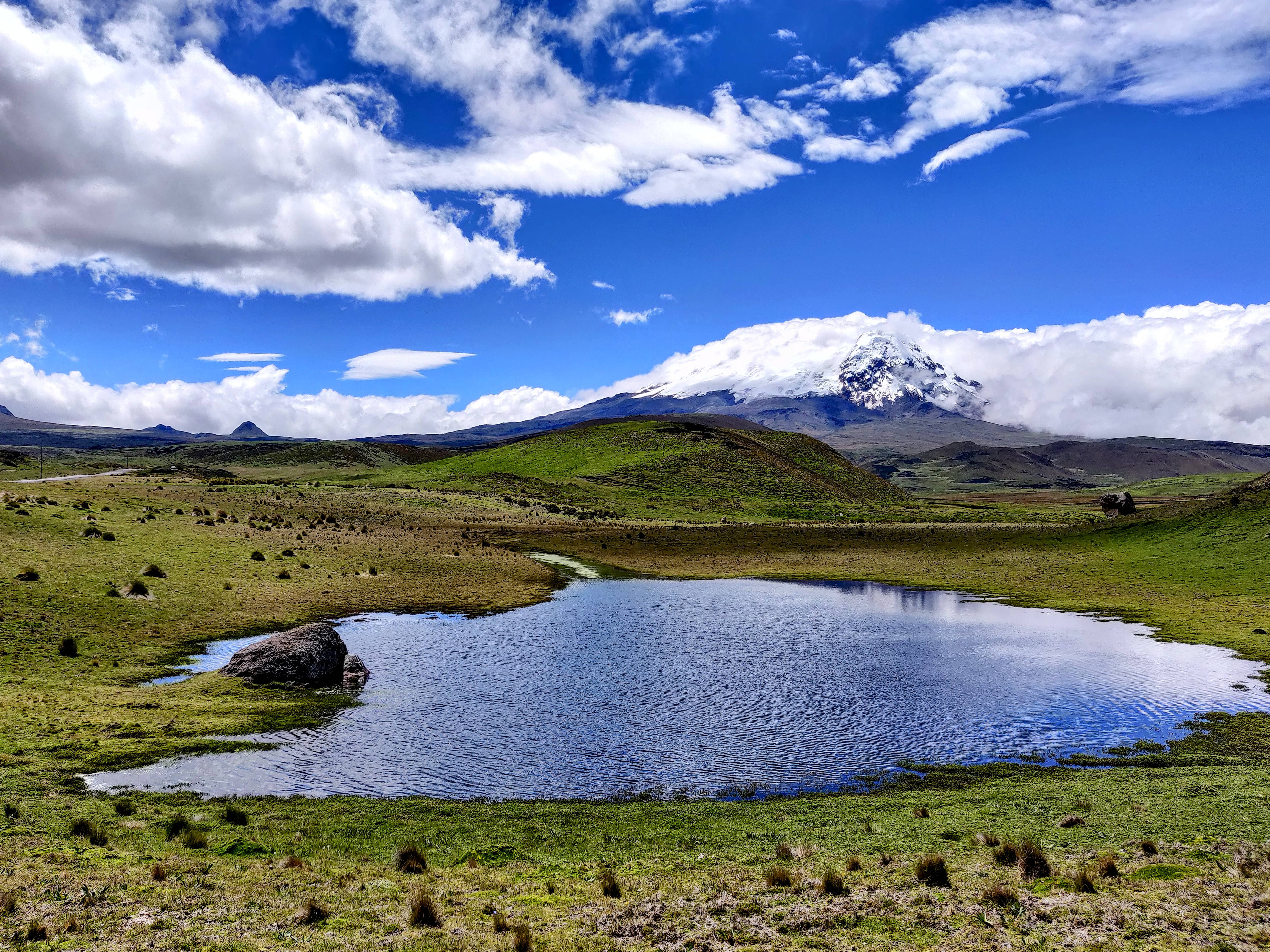 Ecuador 桌布 壁紙 — 寧靜的高山湖泊映照著積雪的山峰，天空湛藍，白雲朵朵。