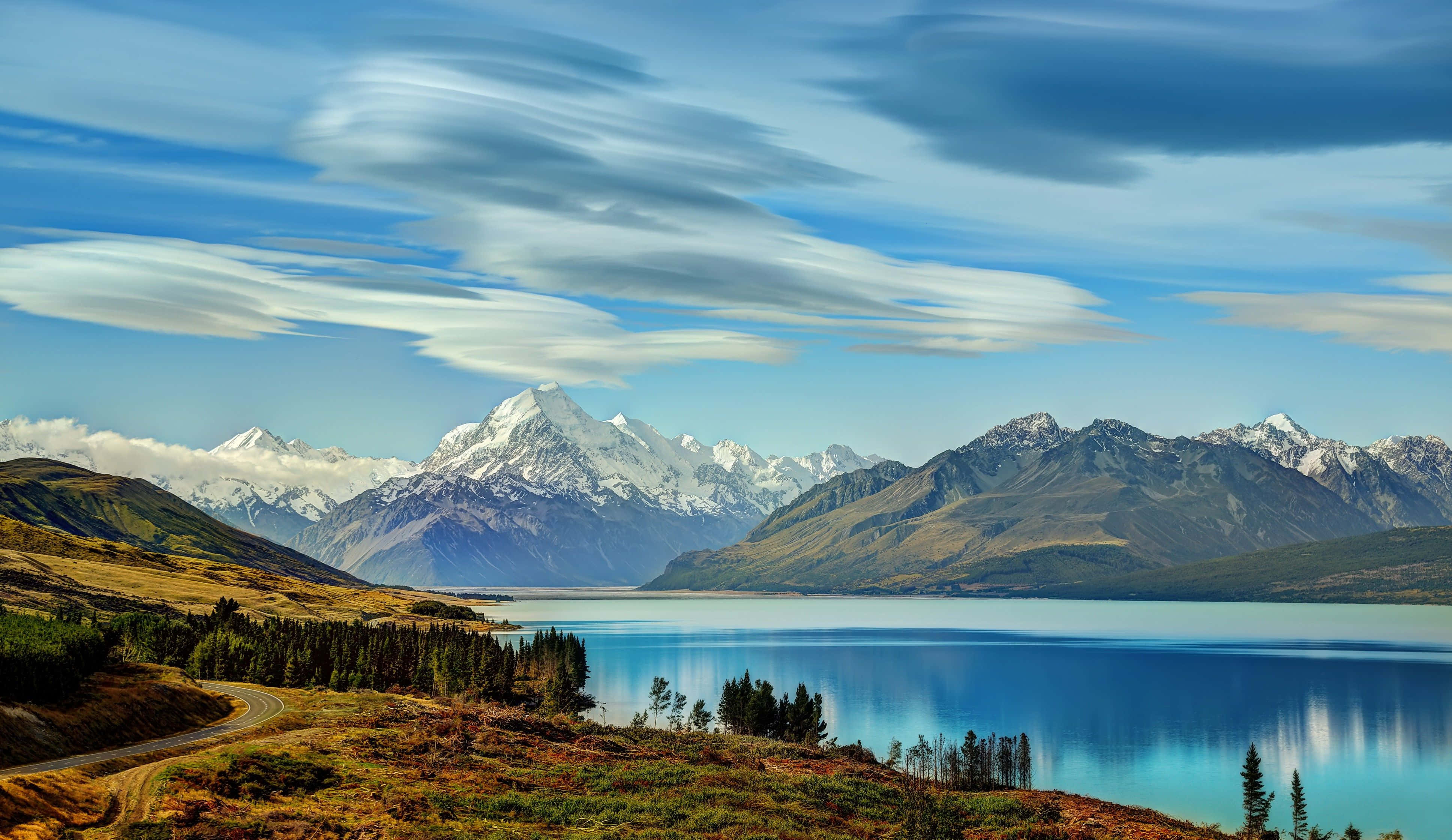Beautiful Lake 桌布 壁紙 — 寧靜的高山湖泊映照著積雪的山峰，天空中有條紋狀的雲彩。