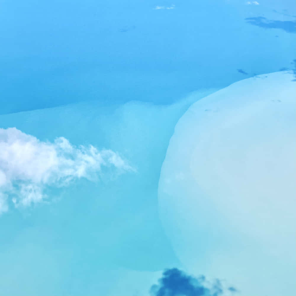 海洋 桌布 壁紙 — 寧靜的鳥瞰圖，碧綠的海洋與白色沙灘相接，蓬鬆的雲朵在頭頂飄過。