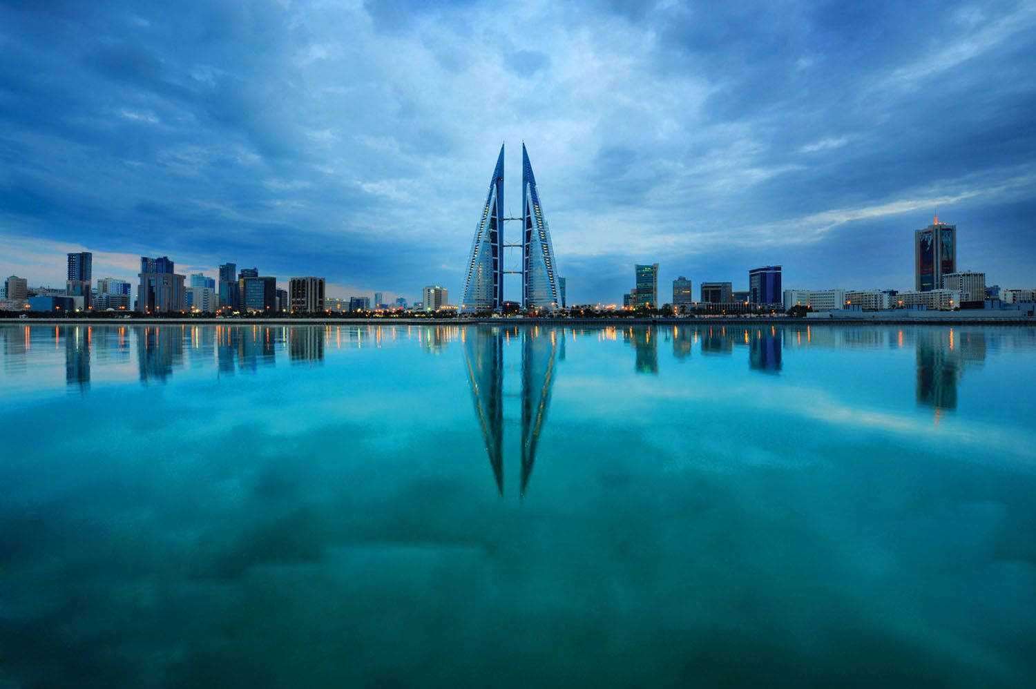 Bahrain 桌布 壁紙 — 寧靜的黃昏城市景觀，標誌性的巴林世界貿易中心雙塔完美倒映在平靜的碧綠海水中。