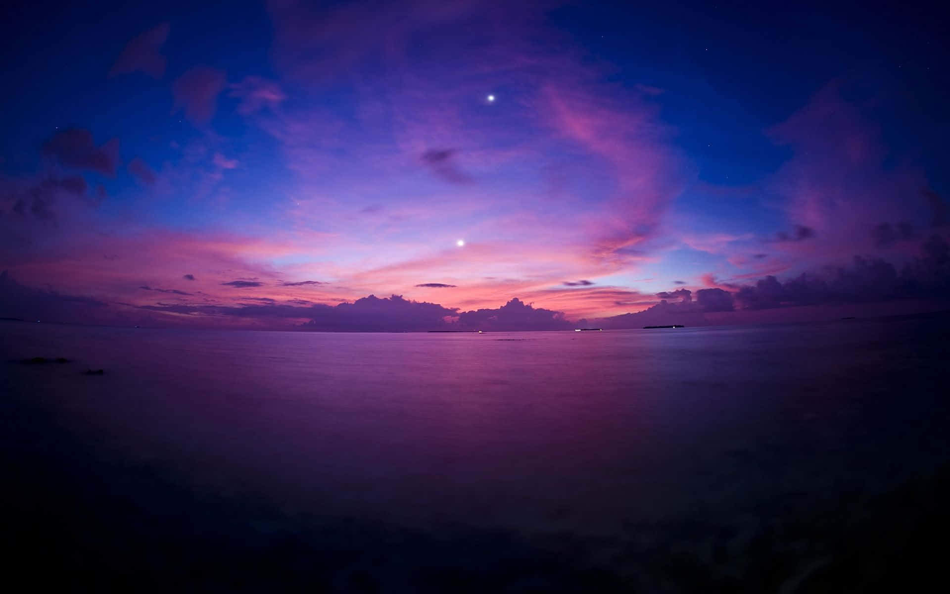 Purple Sunset 桌布 壁紙 — 寧靜的黃昏海景，在星空下，鮮豔的紫色和粉紅色雲彩倒映在平靜的水面上。