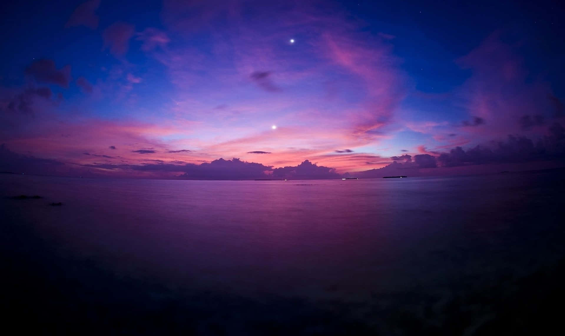 Purple Sunset 桌布 壁紙 — 寧靜的黃昏海景，在星空下，鮮豔的紫色和粉紅色雲彩倒映在平靜的水面上。