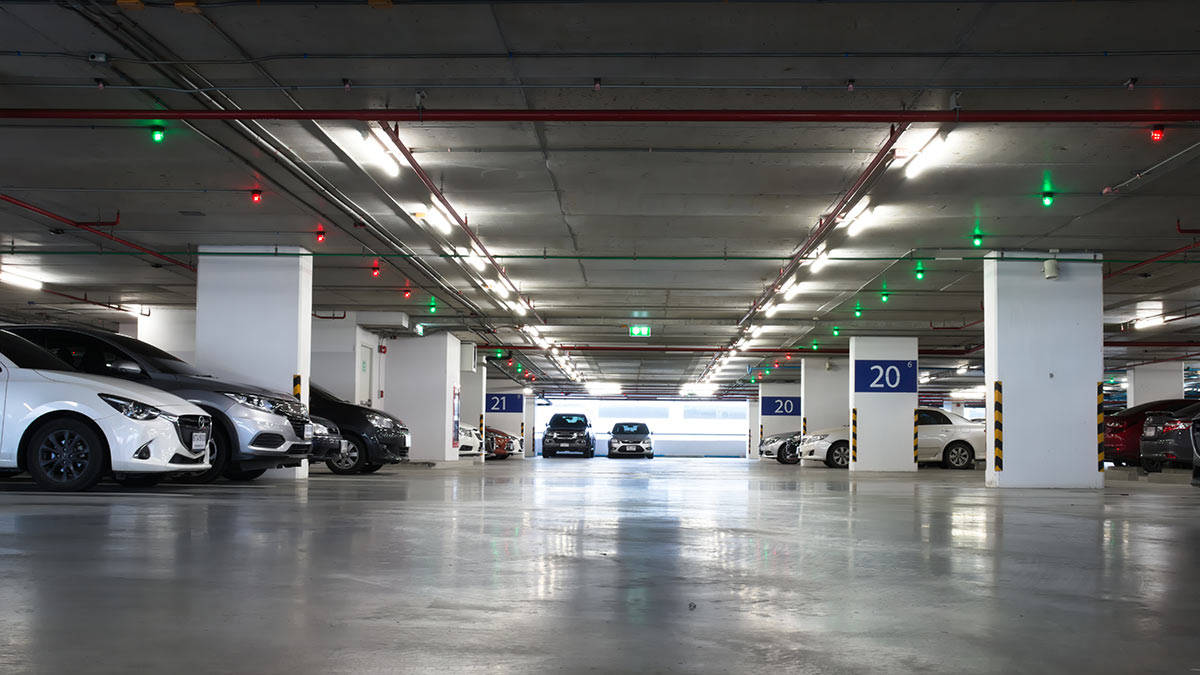 汽車 桌布 壁紙 — 寬敞的地下停車場，拋光混凝土地板，汽車停在明亮的螢光燈下。