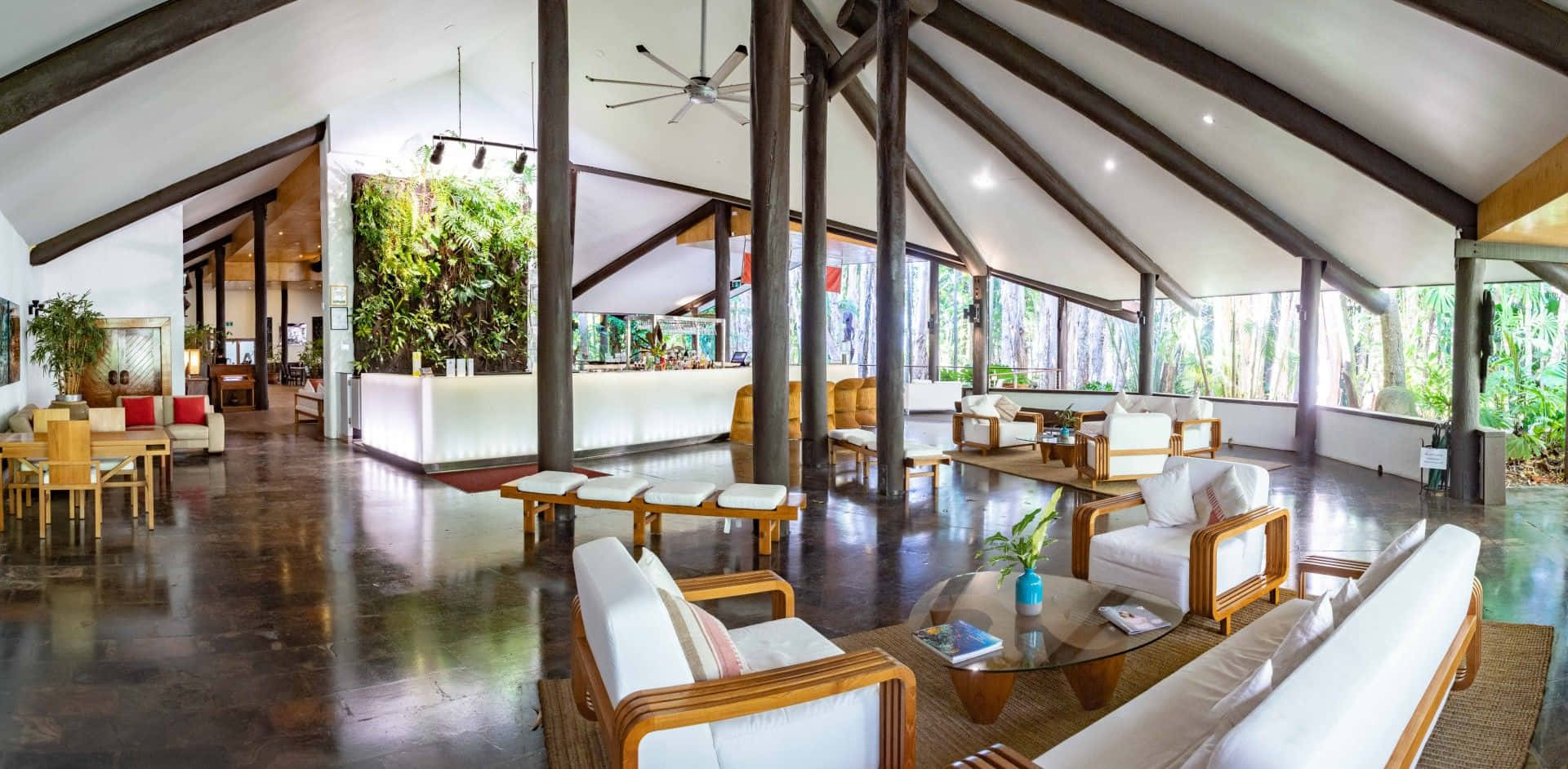 Beach Resort 桌布 壁紙 — 寬敞的熱帶度假村大廳，設有木樑、拋光地板，透過大窗戶可欣賞茂密的綠植。