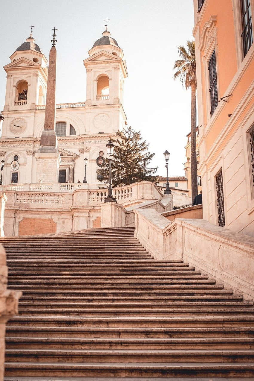 stairs 桌布 壁紙 — 寬闊的石階梯在柔和的金色日光下，通往擁有雙圓頂和方尖碑的歷史羅馬教堂。