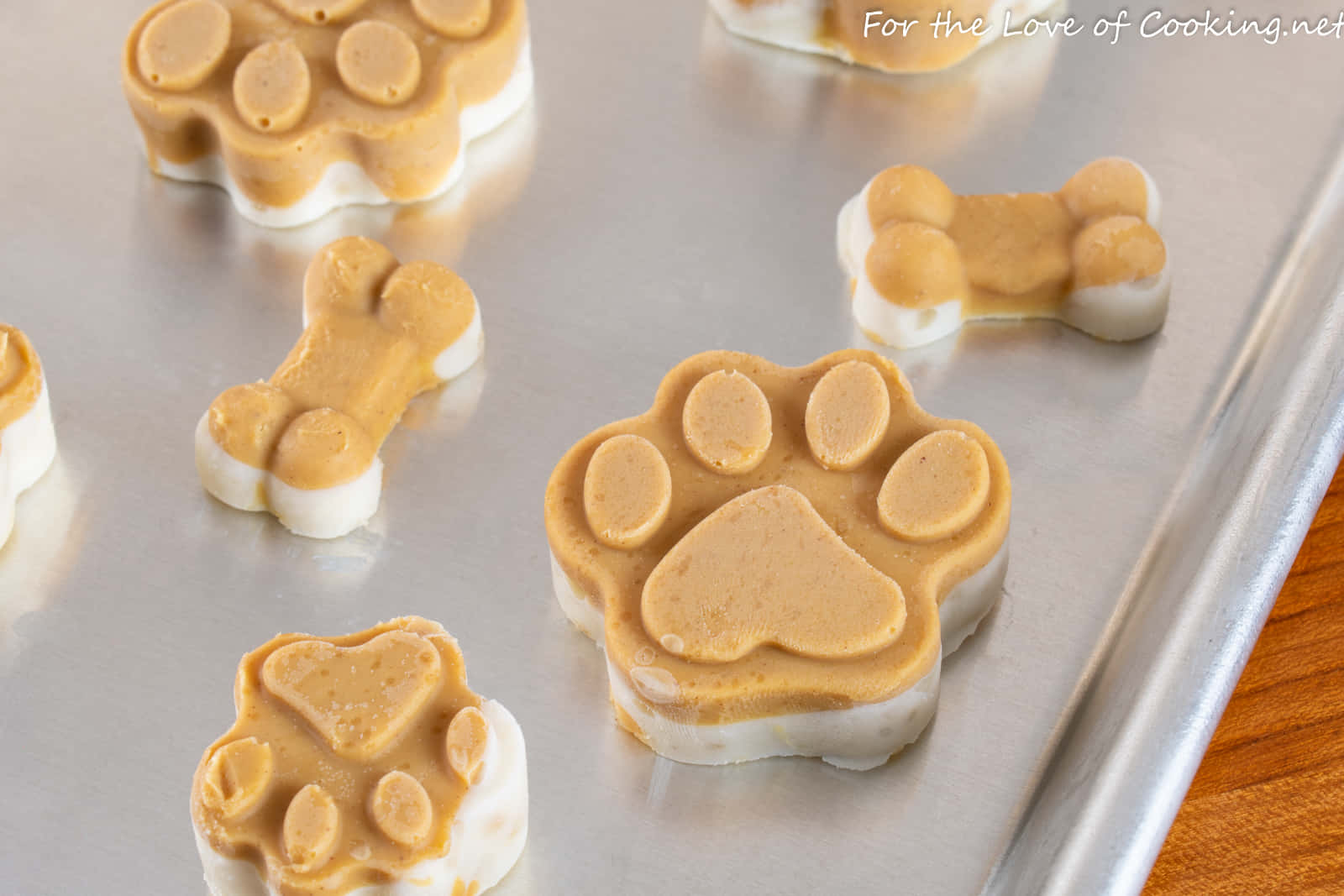 Paw Print 桌布 壁紙 — 寵物零食以爪印和骨頭形狀放在金屬烤盤上，附近有木質表面。