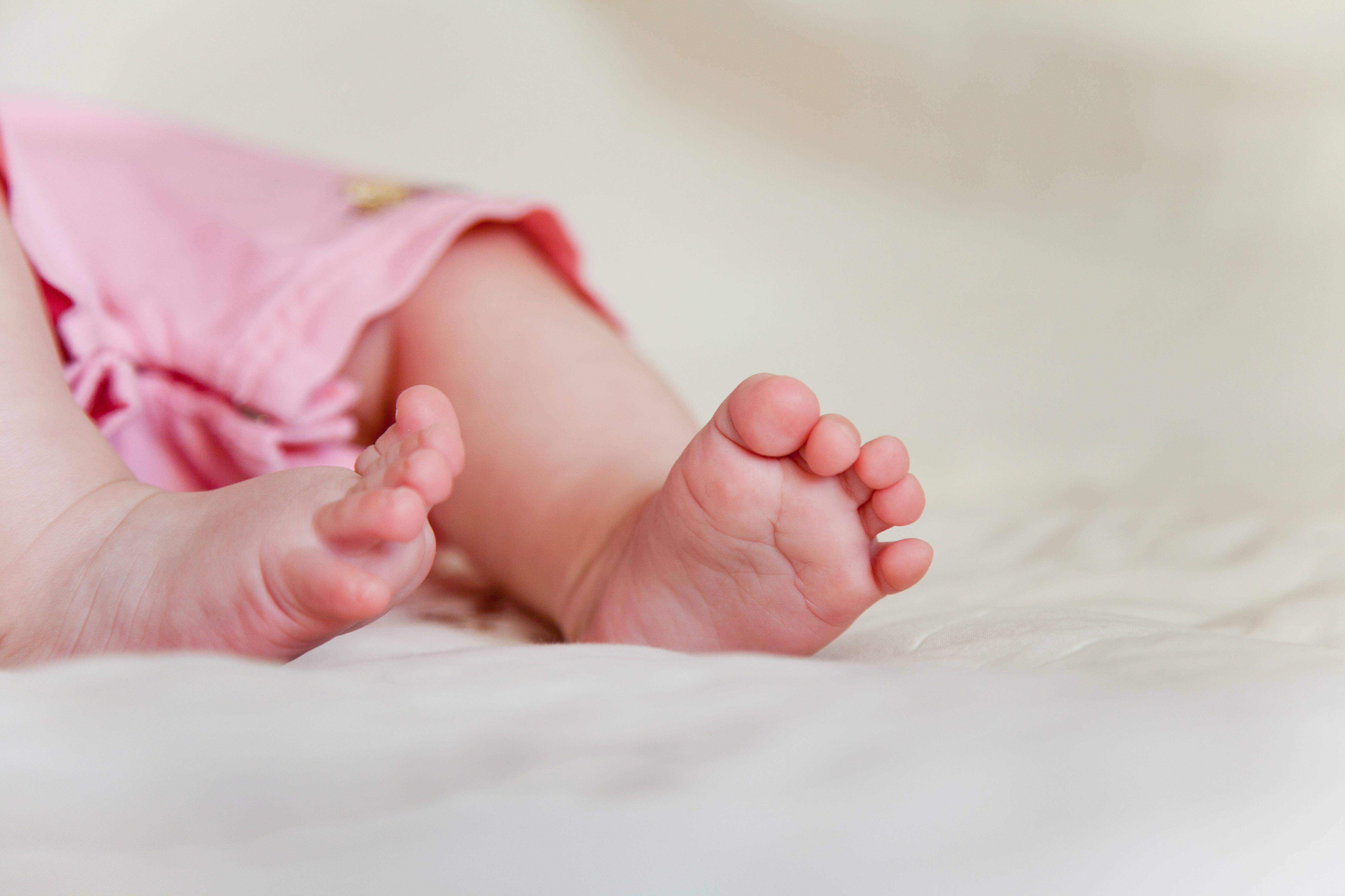 Newborn 桌布 壁紙 — 寶寶穿著粉紅色短褲的小腳丫放在柔軟的白色毯子上的特寫。
