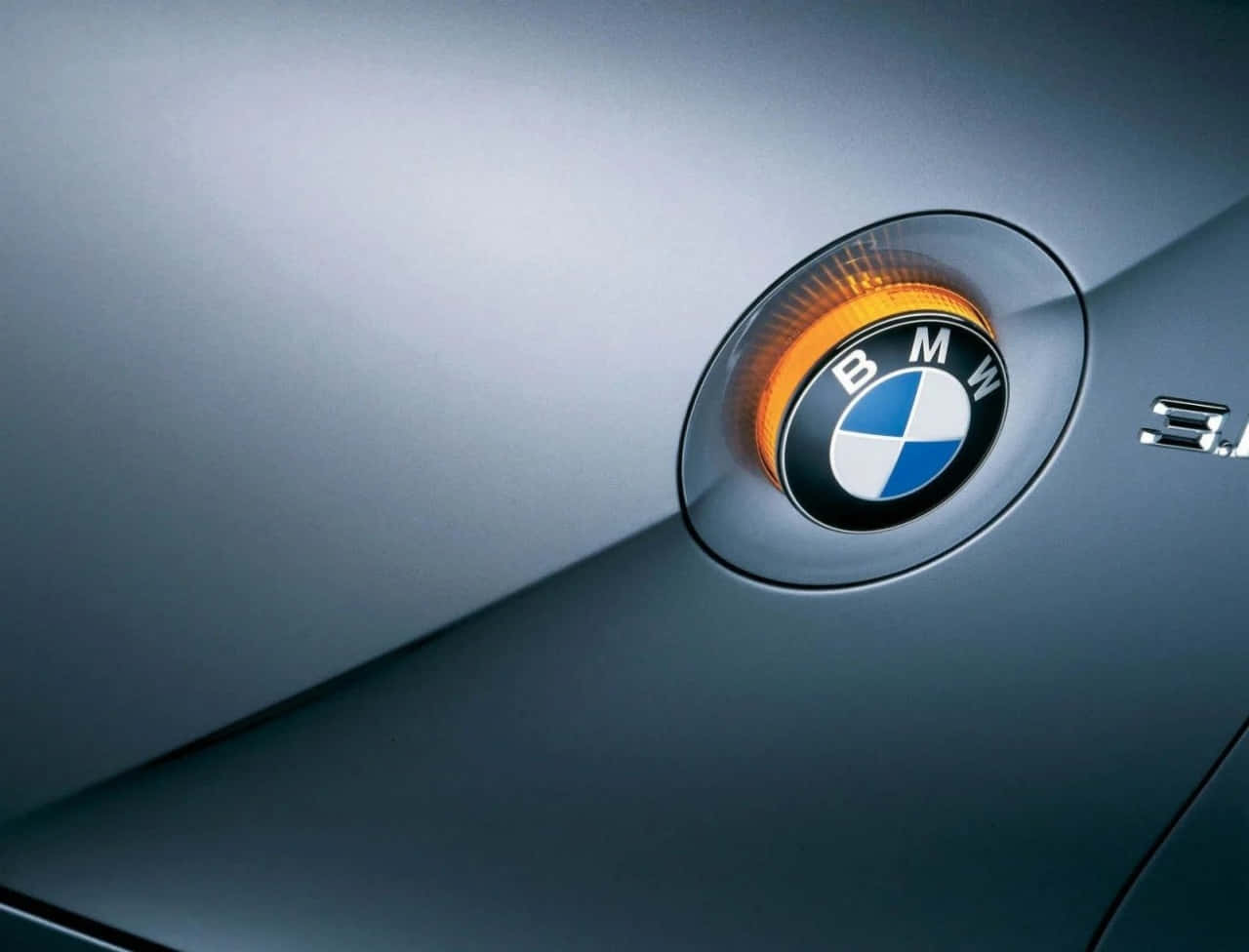 Bmw Logo 桌布 壁紙 — 寶馬標誌特寫，位於時尚銀色引擎蓋上，帶有發光橙色邊框。
