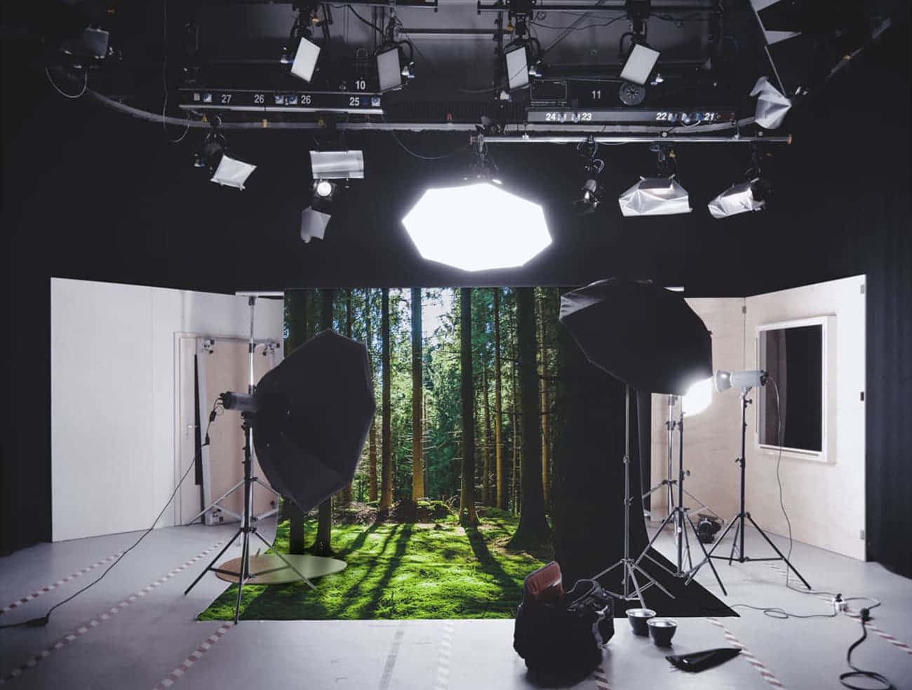 Photography Studio 桌布 壁紙 — 專業攝影工作室，以森林為背景，配備一系列照明設備，在地板上投射出柔和陰影。