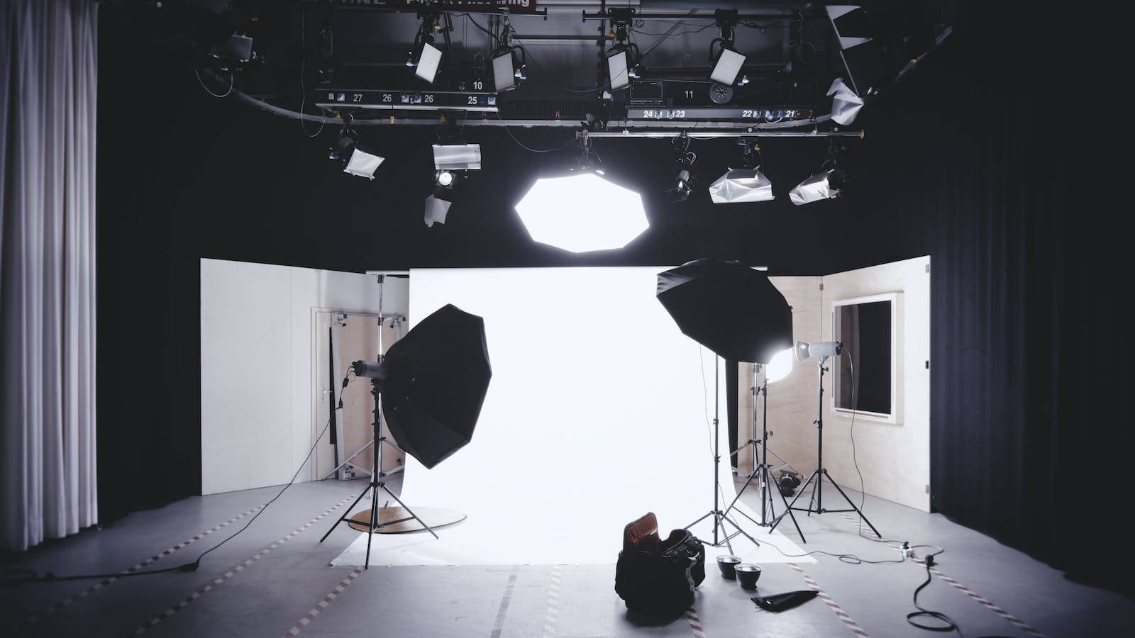Studio 桌布 壁紙 — 專業攝影工作室，配有明亮的白色背景和暗色天花板下的多種照明設備。