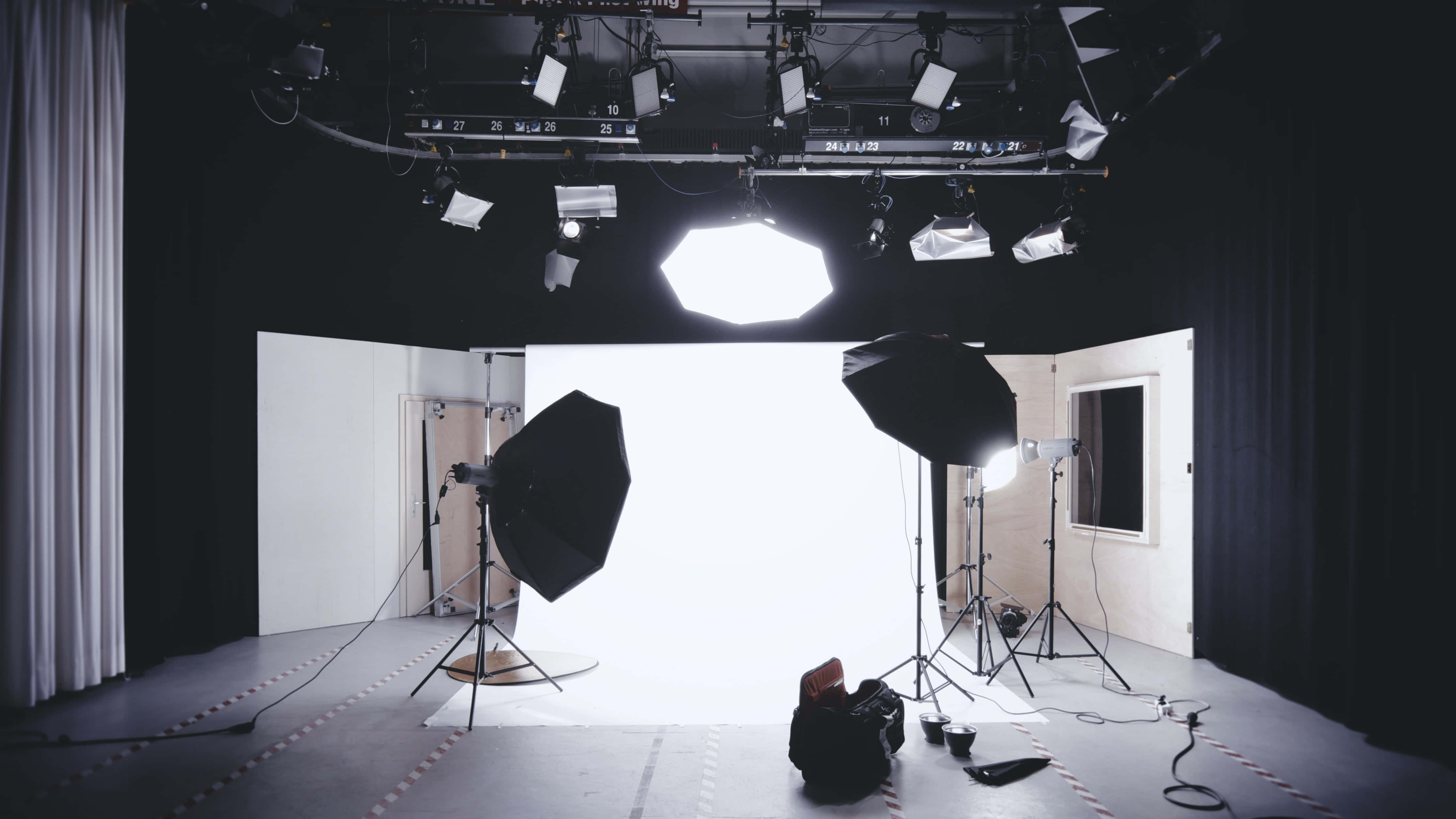 Studio 桌布 壁紙 — 專業攝影工作室，配有明亮的白色背景和頭頂照明設備，在深色地板上投射出柔和陰影。