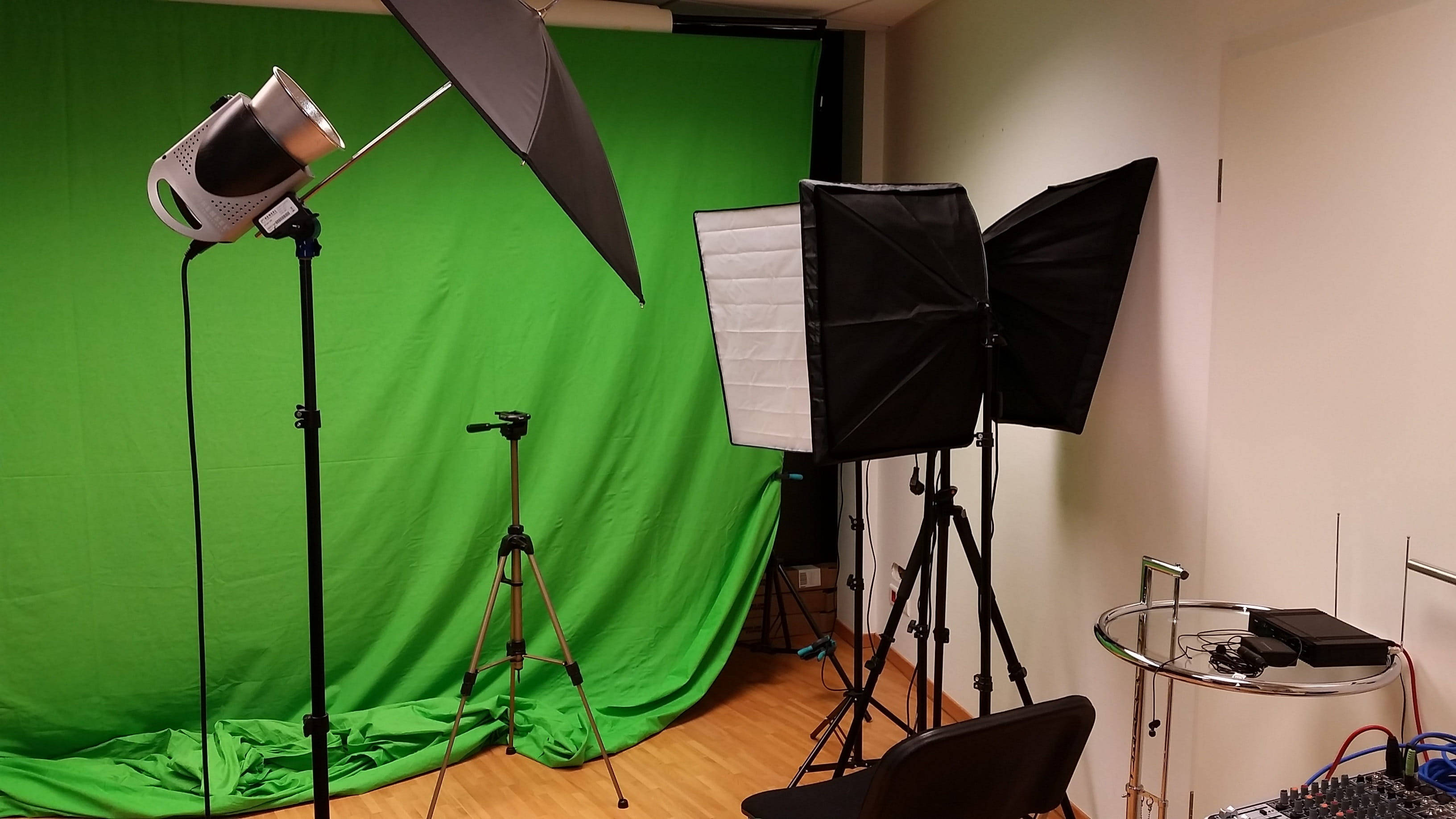 Studio 桌布 壁紙 — 專業攝影棚設置，配備綠幕、燈光設備及三腳架，置於木地板上。