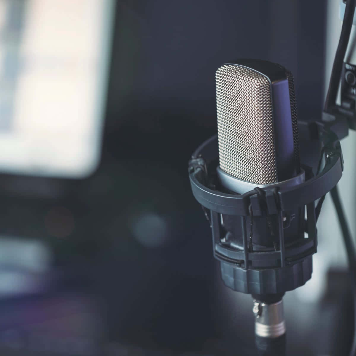 Podcast 桌布 壁紙 — 專業錄音室麥克風的特寫，配有防噴罩和防震架，背景為深色模糊。