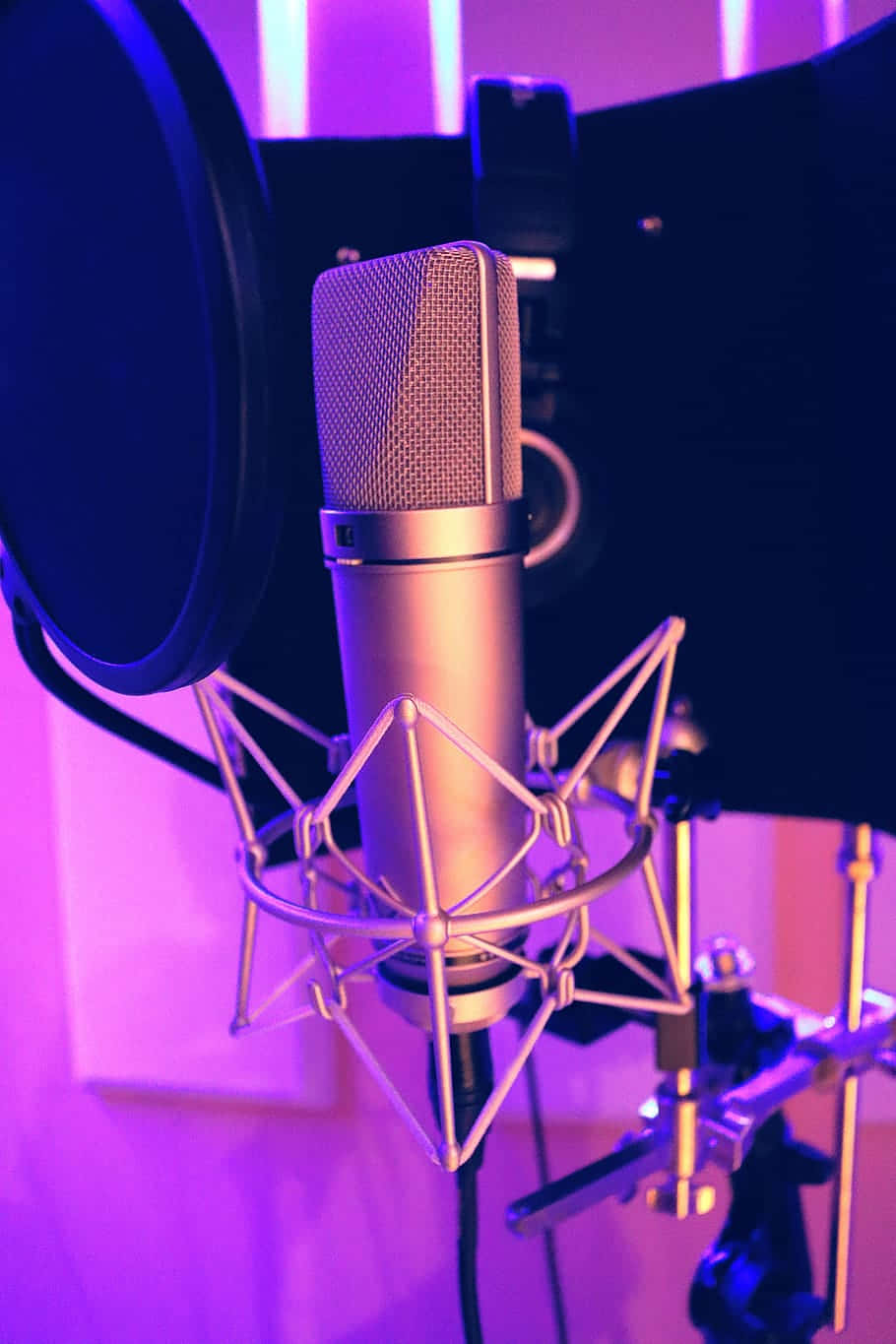 Sound 桌布 壁紙 — 專業電容麥克風安裝在防震架上，沐浴在充滿活力的紫色錄音室燈光中。