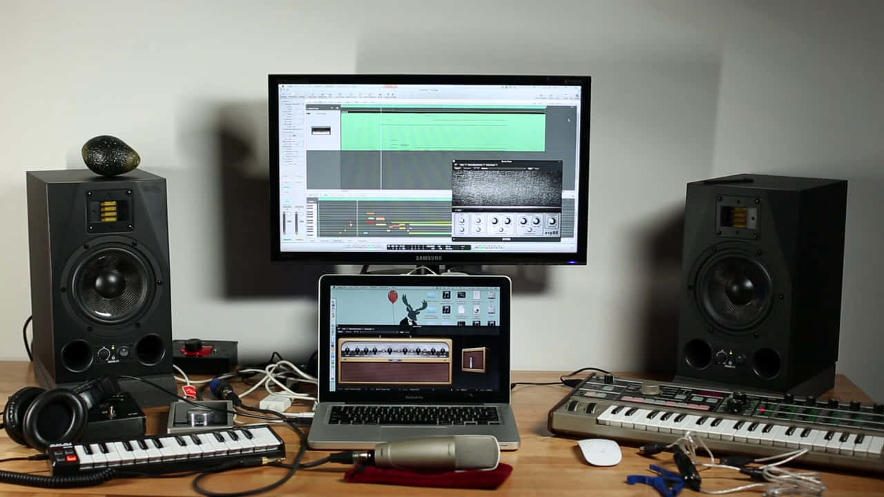 Music Video 桌布 壁紙 — 專業音樂製作設置，配備顯示器、鍵盤、揚聲器和麥克風，置於木桌上。