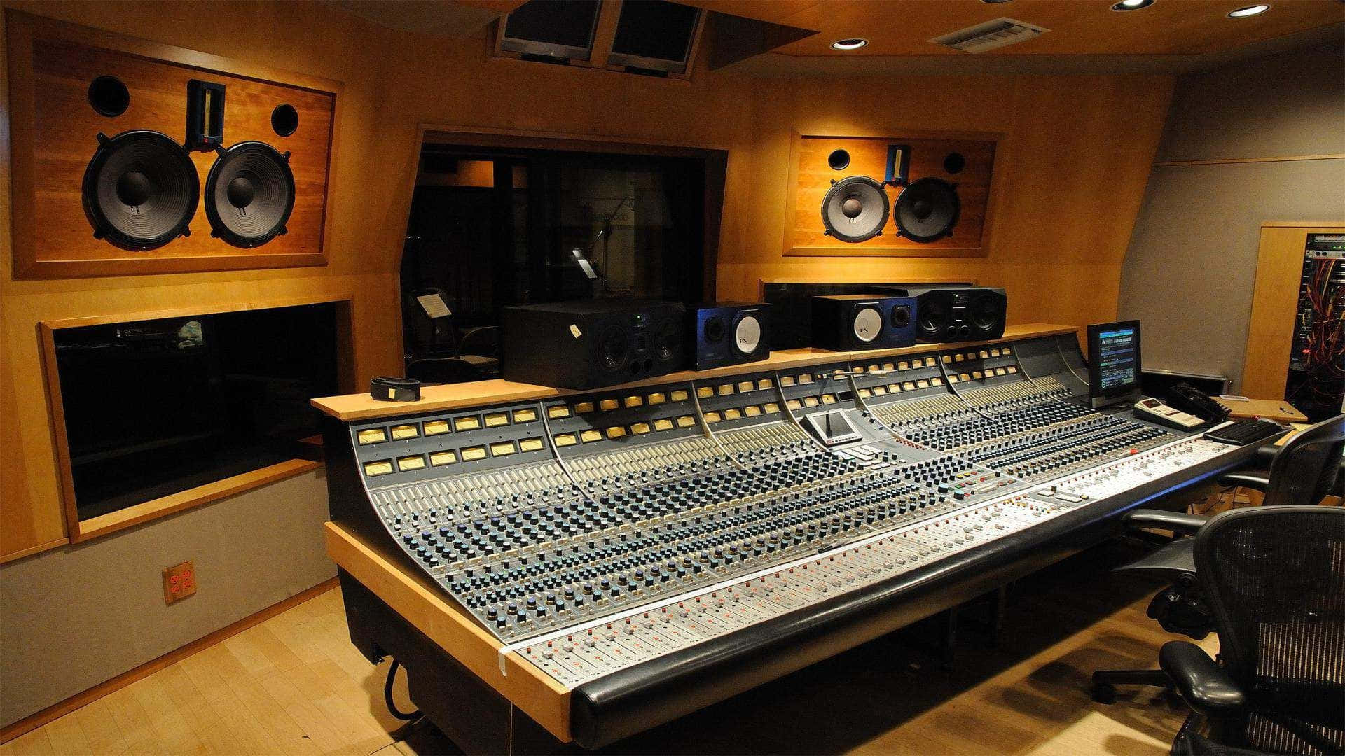 Studio 桌布 壁紙 — 專業音頻混音台，位於溫暖照明的錄音室，配有木牆和錄音室監聽器。