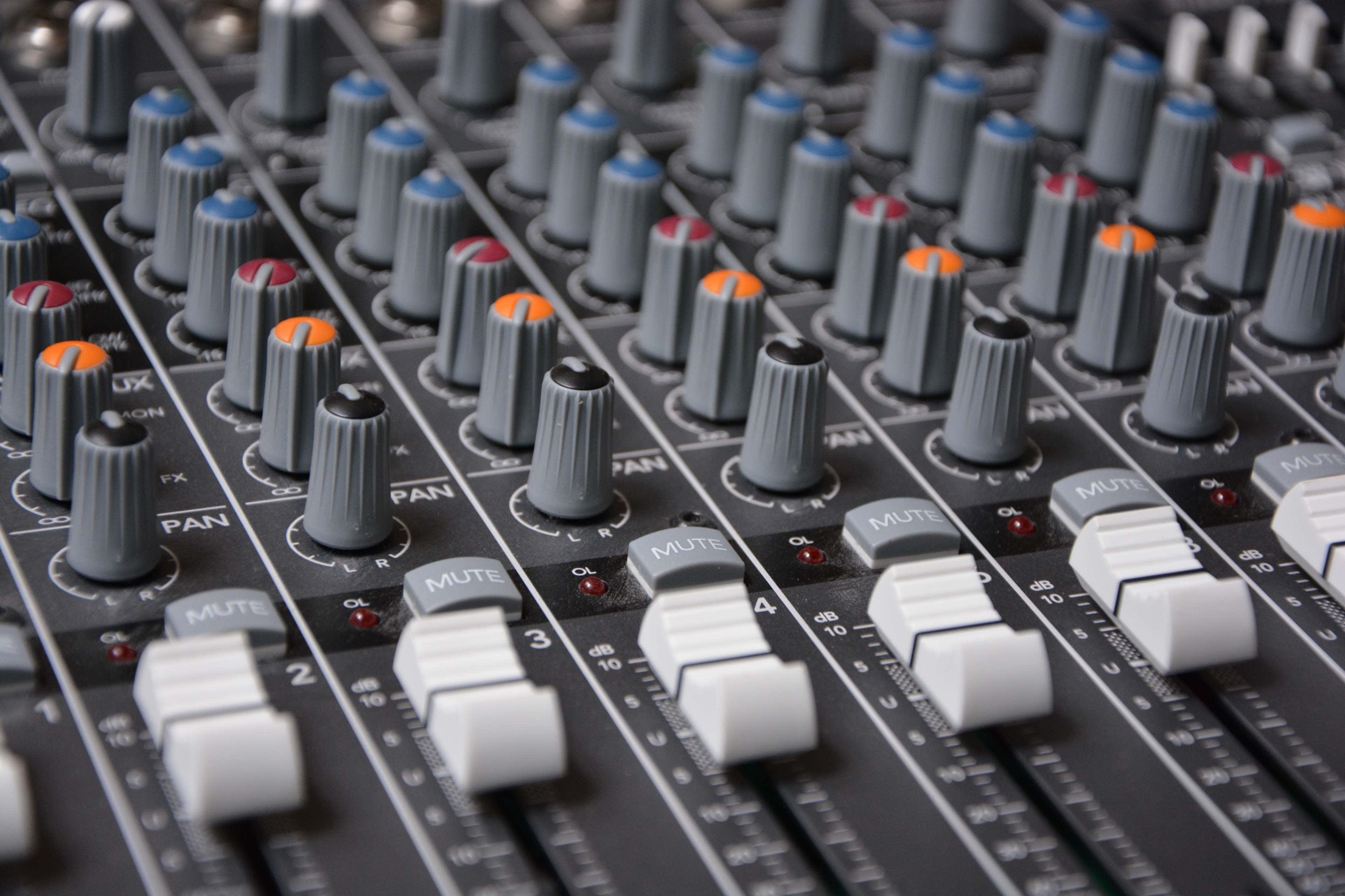 Studio 桌布 壁紙 — 專業音頻混音控制台的近距離特寫，帶有灰色旋鈕和白色推子。