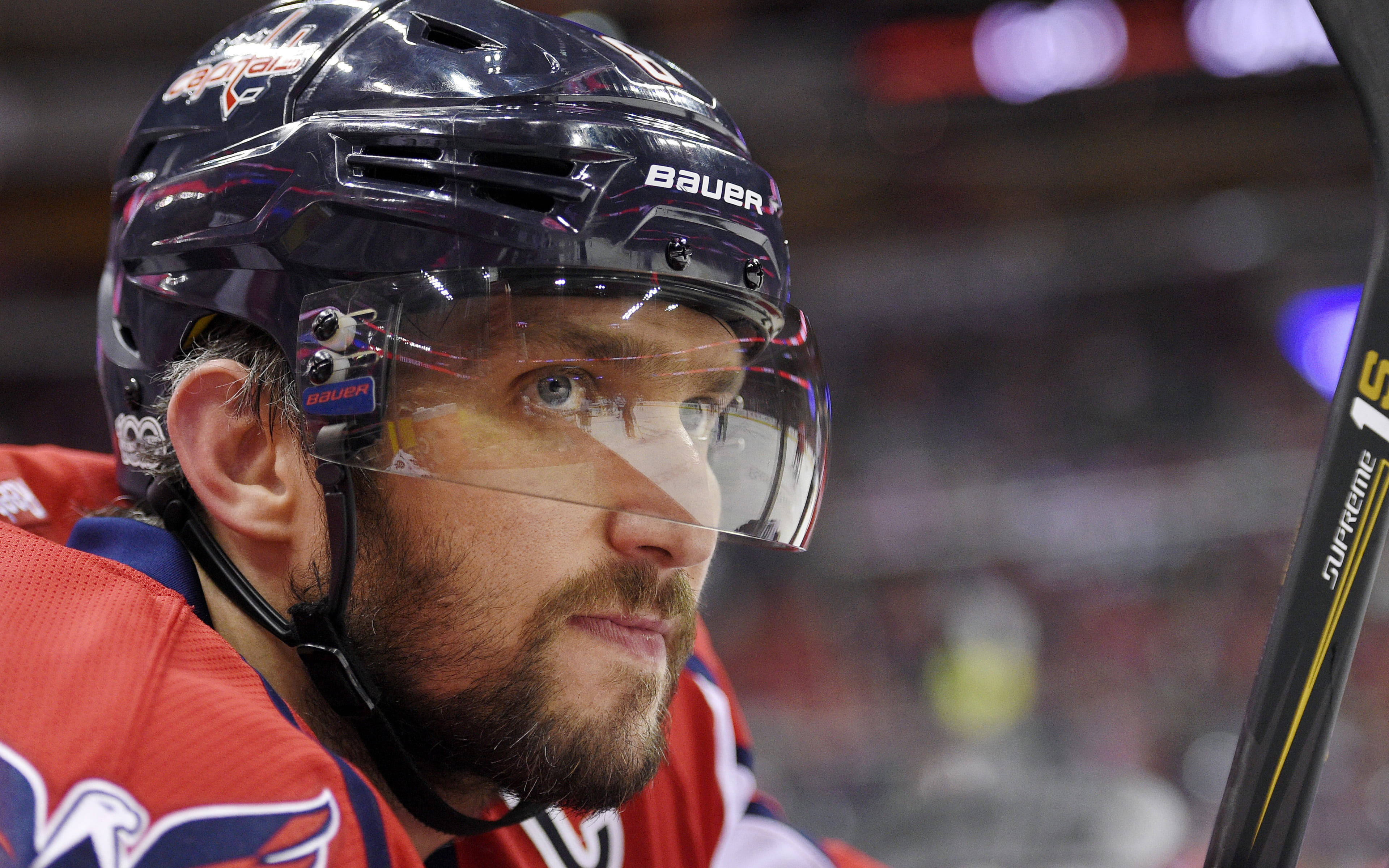 Washington Capitals 桌布 壁紙 — 專注的冰球運動員身穿紅色球衣和黑色頭盔，在冰上持棍的特寫。