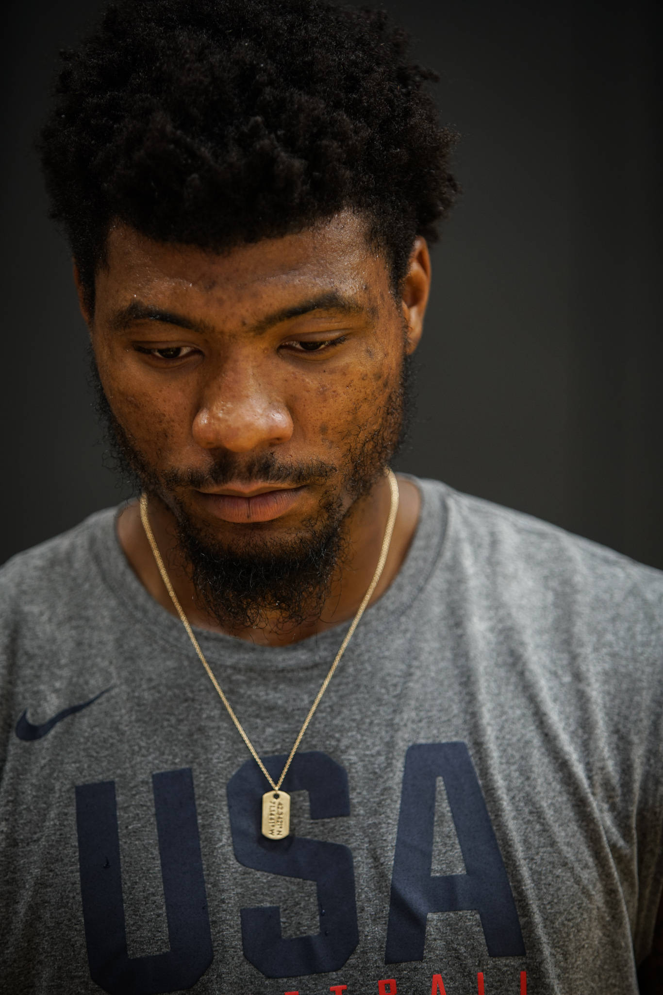 Marcus 桌布 壁紙 — 專注的籃球運動員穿著美國球衣，戴著狗牌項鍊，在深色背景前的特寫肖像。