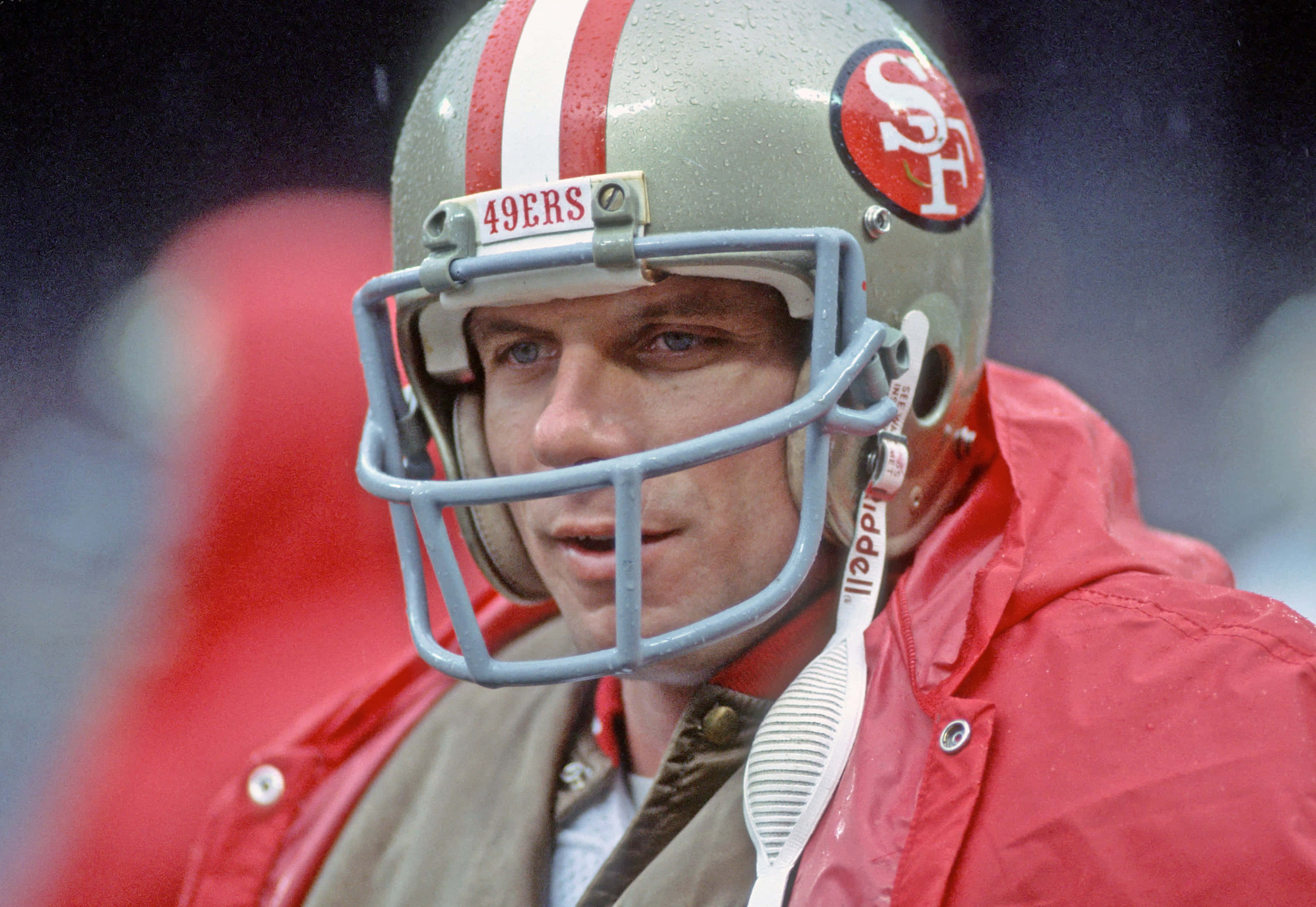 Joe Montana 桌布 壁紙 — 專注的舊金山49人美式足球員在比賽中，戴著銀色頭盔和紅色外套的特寫。