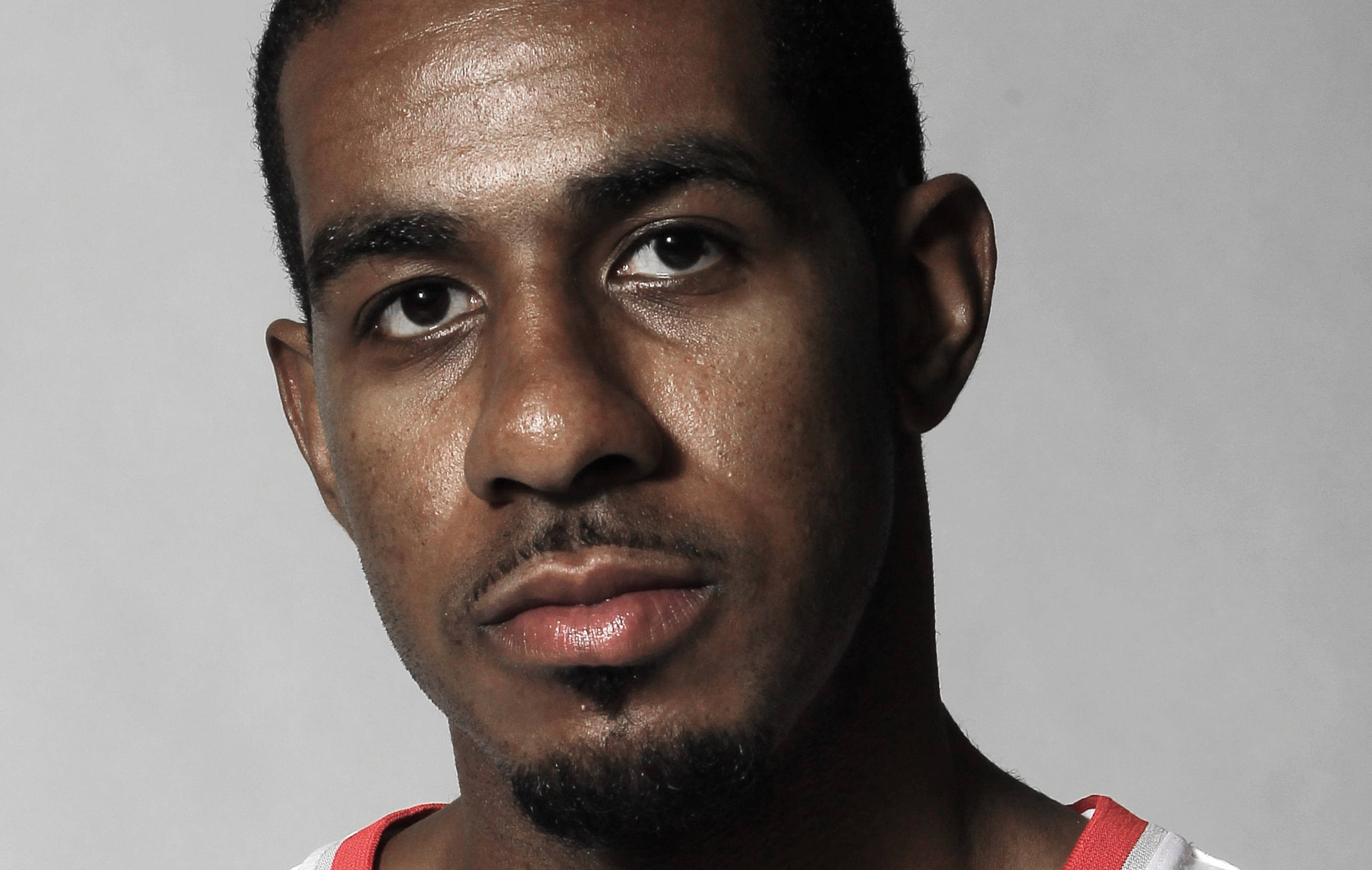 Lamarcus Aldridge 桌布 壁紙 — 專注的黑人男子特寫肖像，短髮和鬍渣，穿著紅白運動球衣，背景為純灰色。