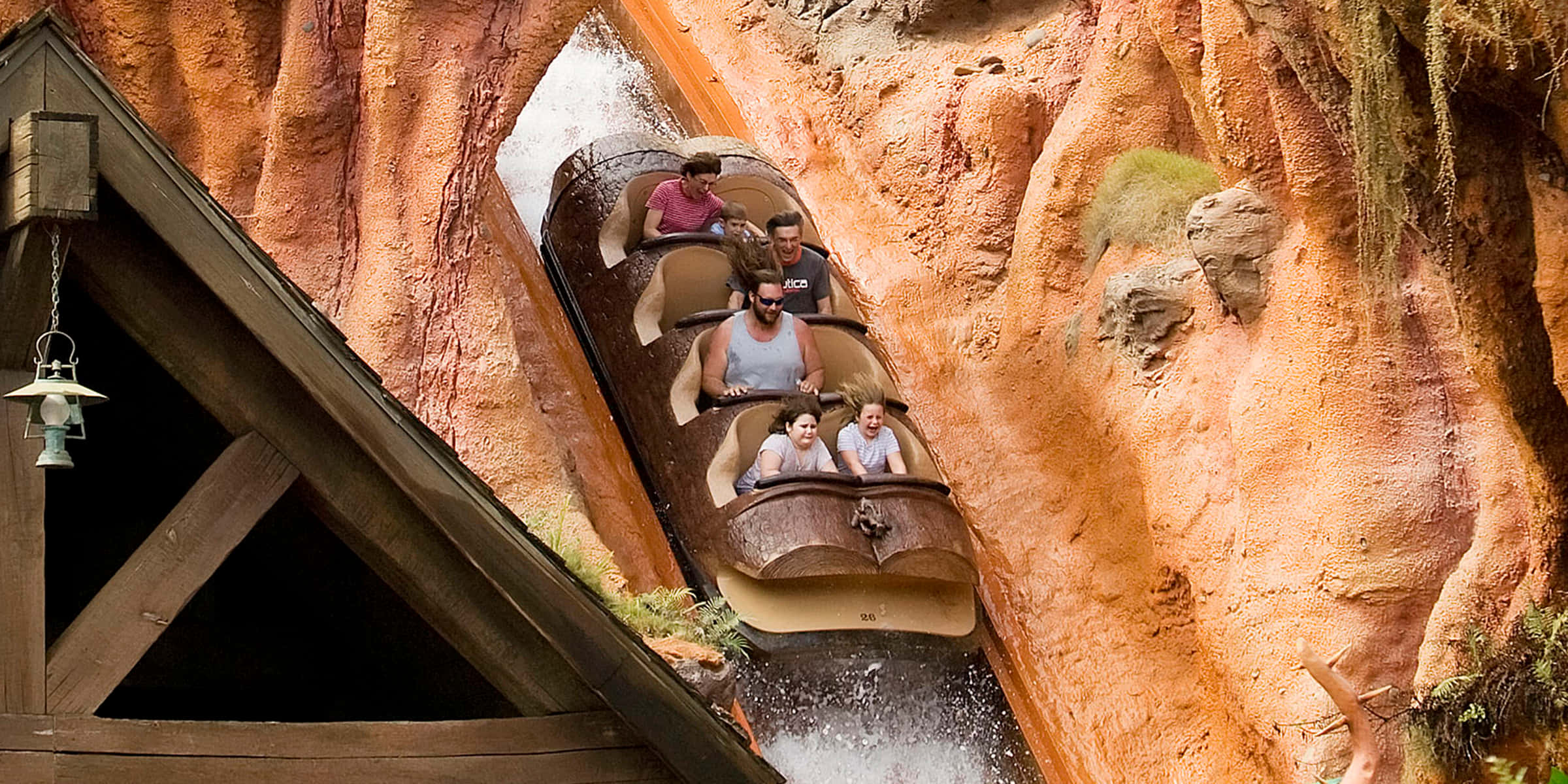 Splash Mountain 桌布 壁紙 — 尋求刺激的人乘坐原木水槽船衝過崎嶇的橙色峽谷，附近有水花飛濺和木結構。