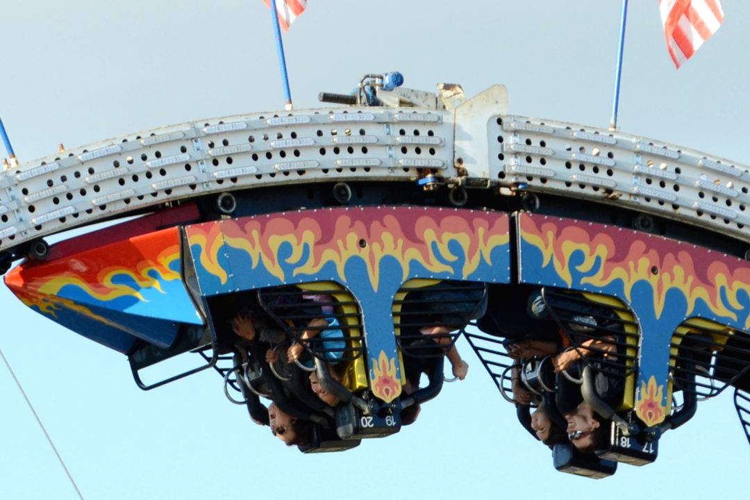 Roller Coaster 桌布 壁紙 — 尋求刺激的人倒掛在火紅藍色的遊樂園遊樂設施上，背景是晴朗的天空。