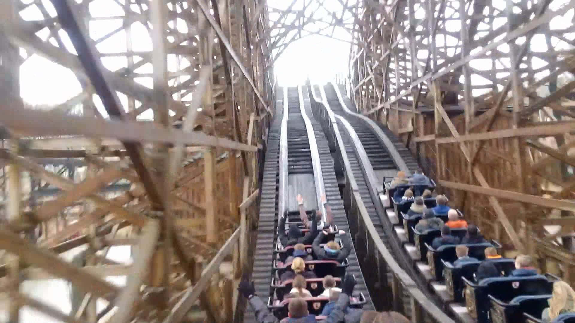 Roller Coaster 桌布 壁紙 — 尋求刺激的人在多雲的天空下攀登一座高聳的木製雲霄飛車軌道。