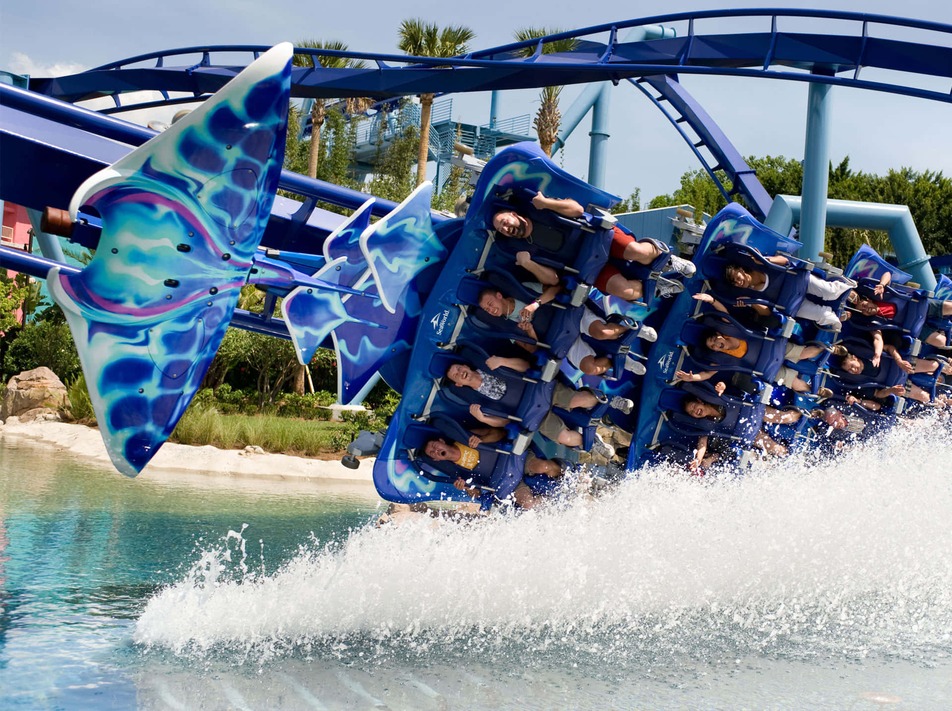 Seaworld 桌布 壁紙 — 尋求刺激的人在晴朗的天空下，藍色水上雲霄飛車衝入水花池時，高興地尖叫。