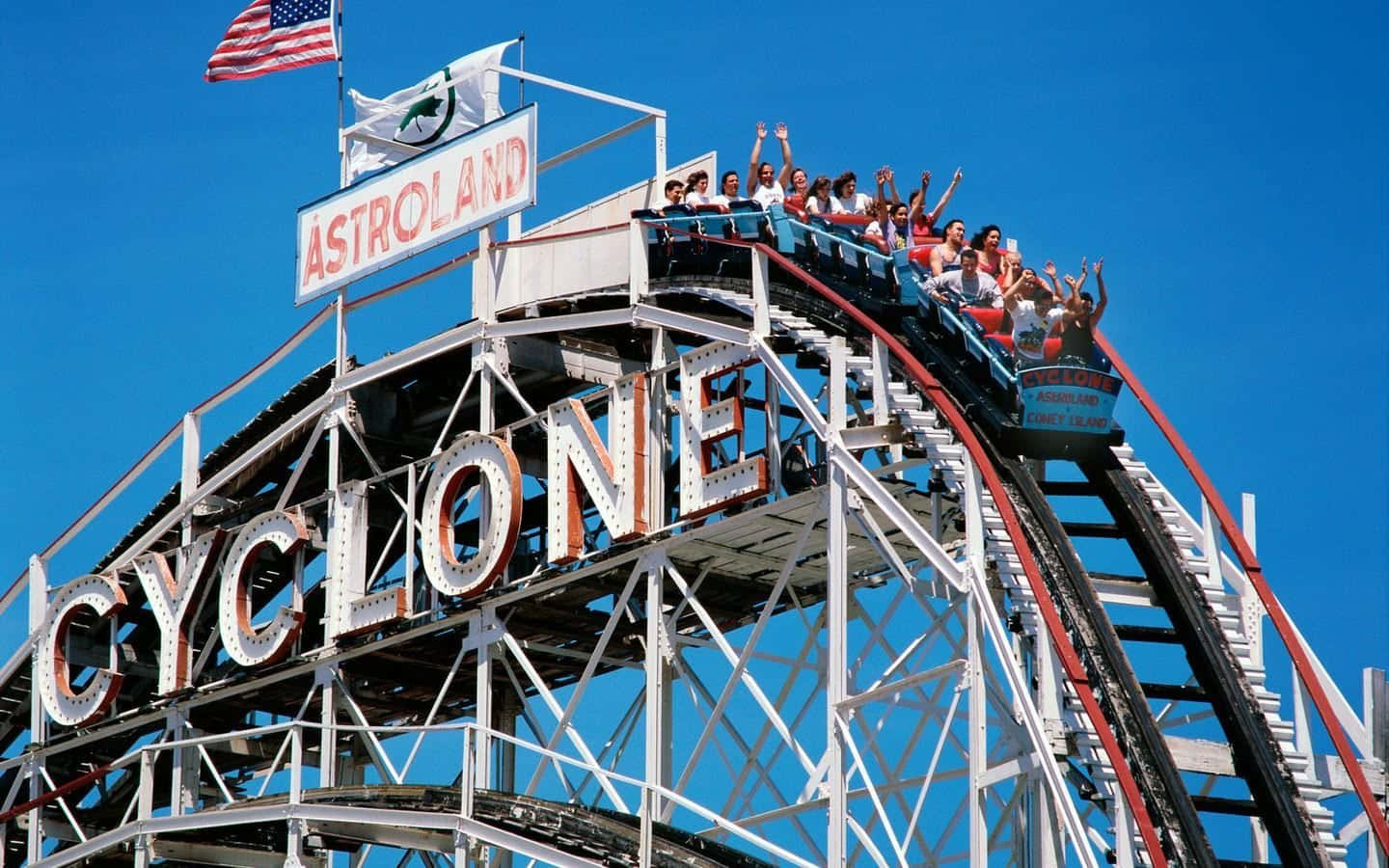 Roller Coaster 桌布 壁紙 — 尋求刺激的人在晴朗的藍天下，登上阿斯楚蘭德高聳的旋風雲霄飛車頂峰時，興奮地尖叫。