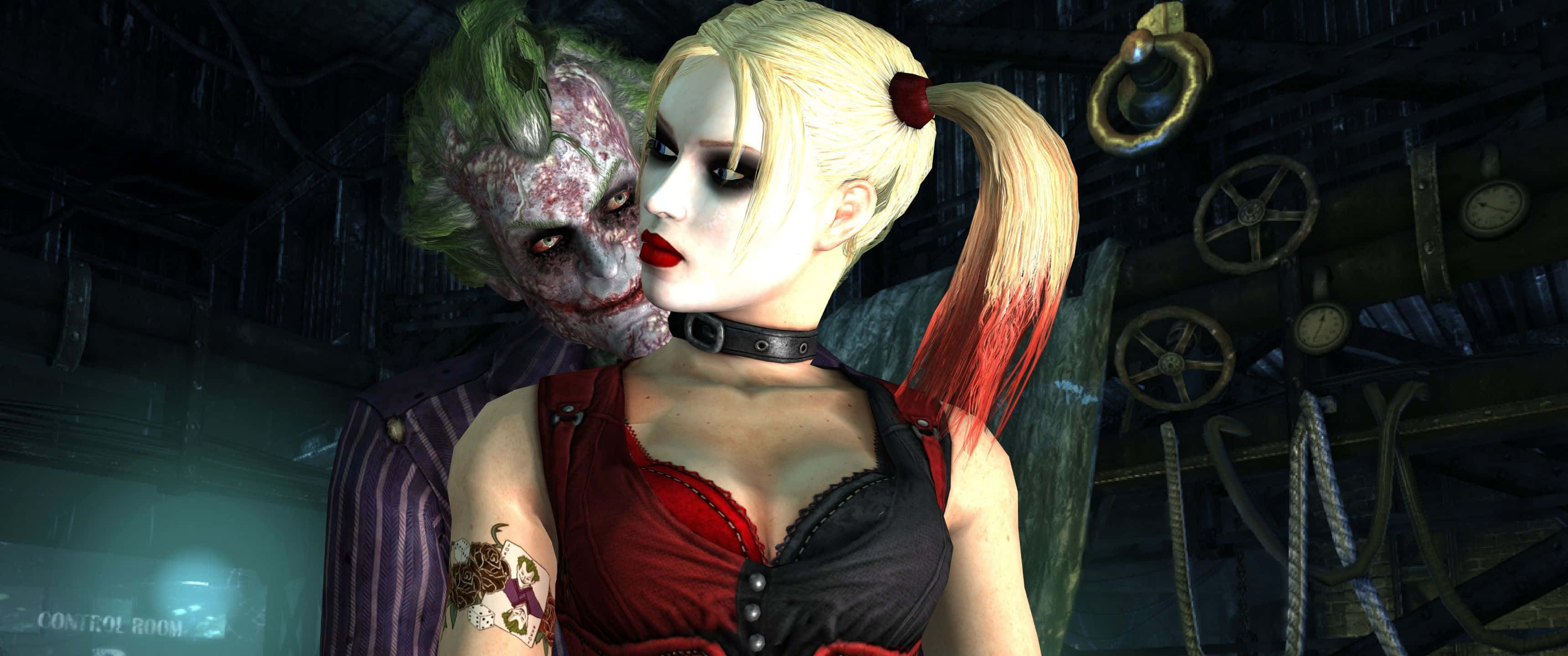 3440x1440p Batman Arkham City 桌布 壁紙 — 小丑和哈莉·奎茵在一個光線昏暗的控制室裡緊密站著，室內充滿工業設備和懸掛的繩索。