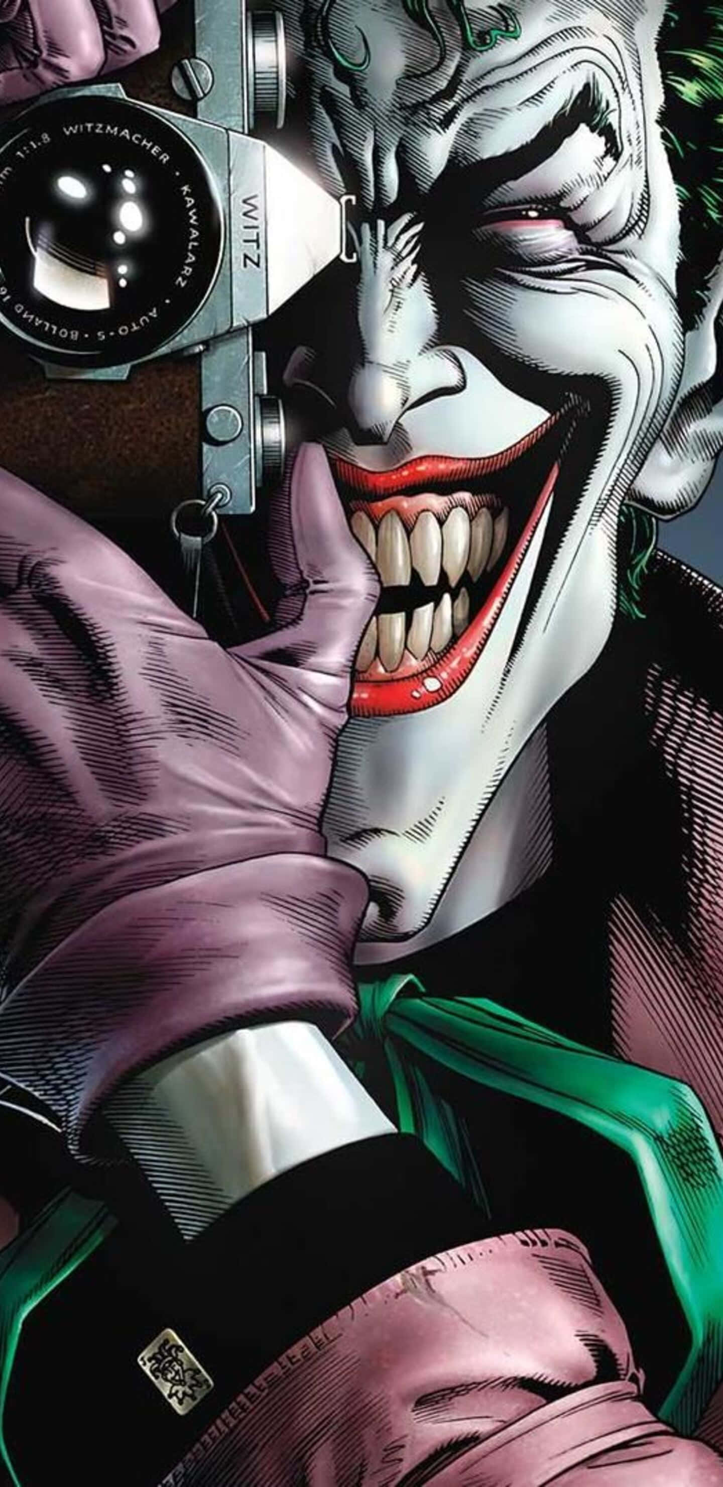 The Killing Joke 桌布 壁紙 — 小丑在漫畫插圖中，拿著一部復古相機貼近臉部，露出瘋狂的笑容。