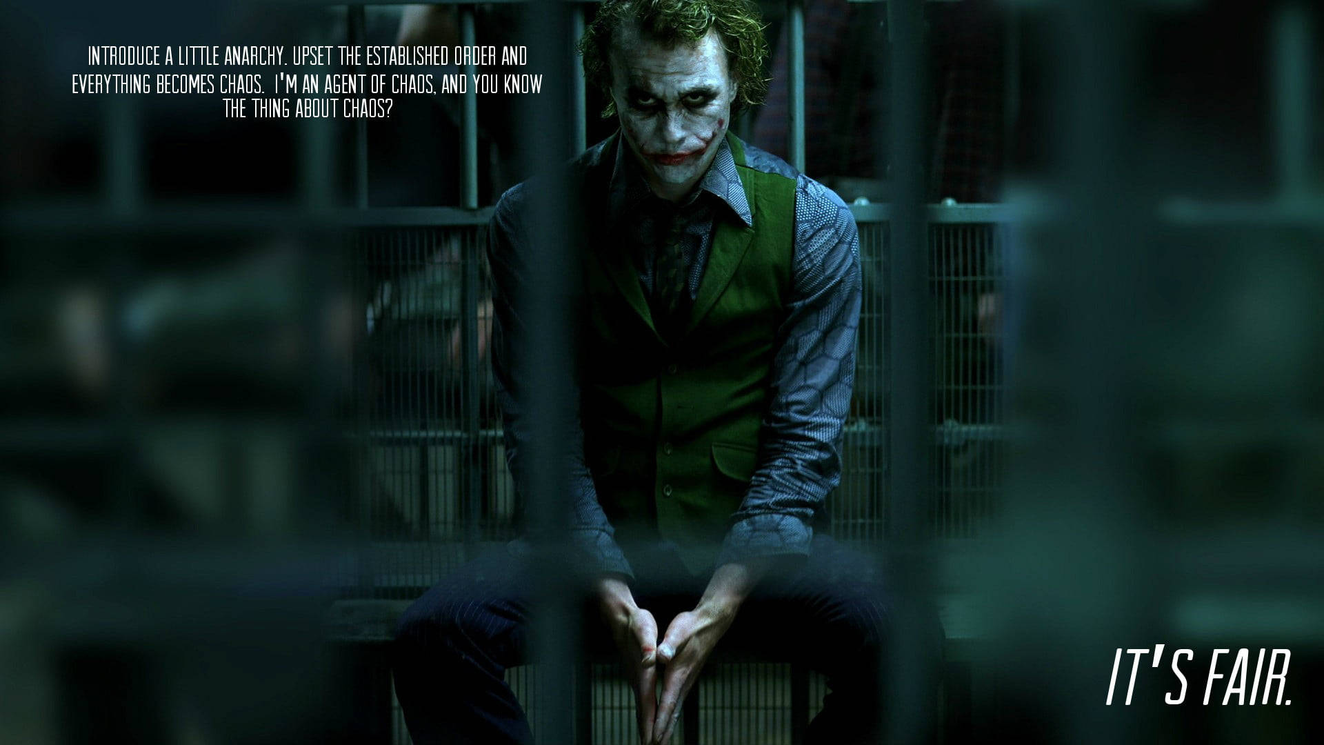 Heath Ledger Joker 桌布 壁紙 — 小丑坐在昏暗牢房的鐵欄後，身穿綠色背心，白色臉部化妝，紅唇。