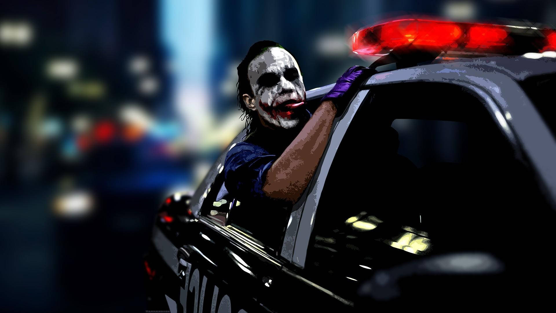 桌布 壁紙 — 小丑從警車中探出身子，紅色燈光在模糊的城市夜景背景下閃爍。