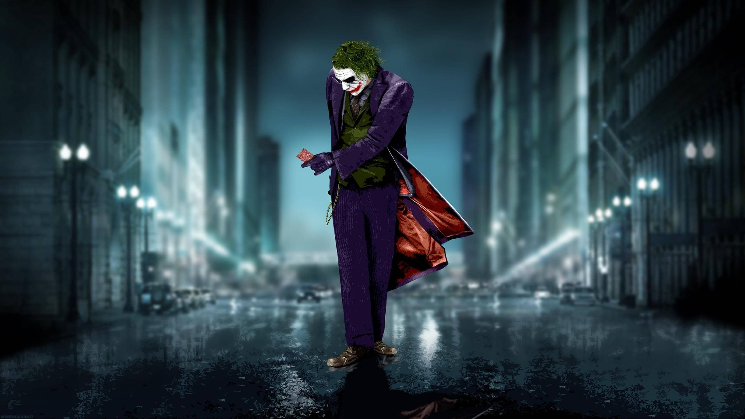 Heath Ledger Joker 桌布 壁紙 — 小丑獨自站在夜間被雨水浸濕的哥譚街道上，他的紫色西裝和綠色頭髮在街燈下閃耀。